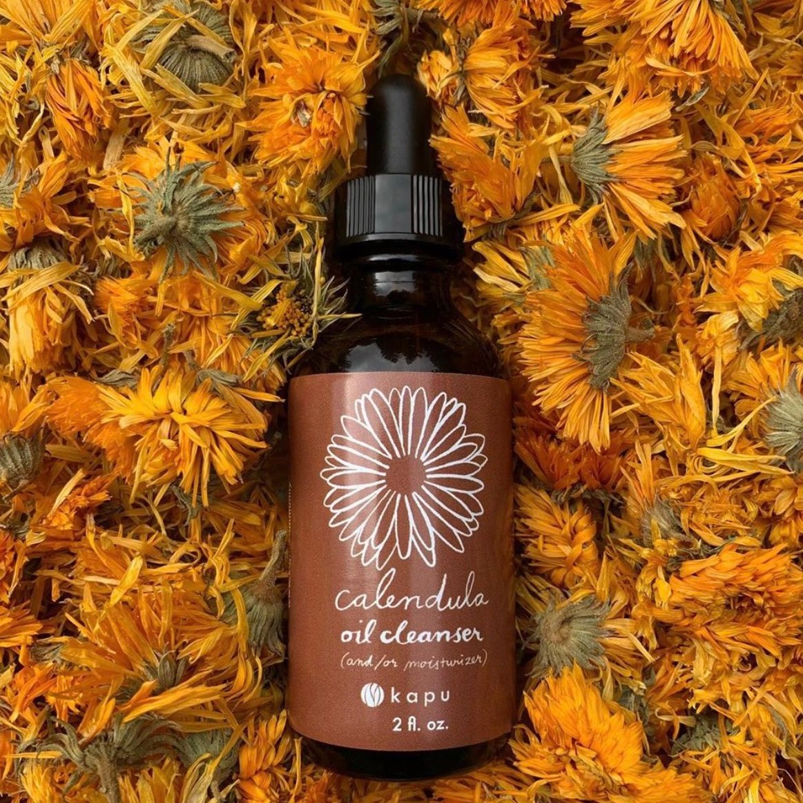 Kapu Community Calendula Oil Cleanser bottle on a bed of calendula