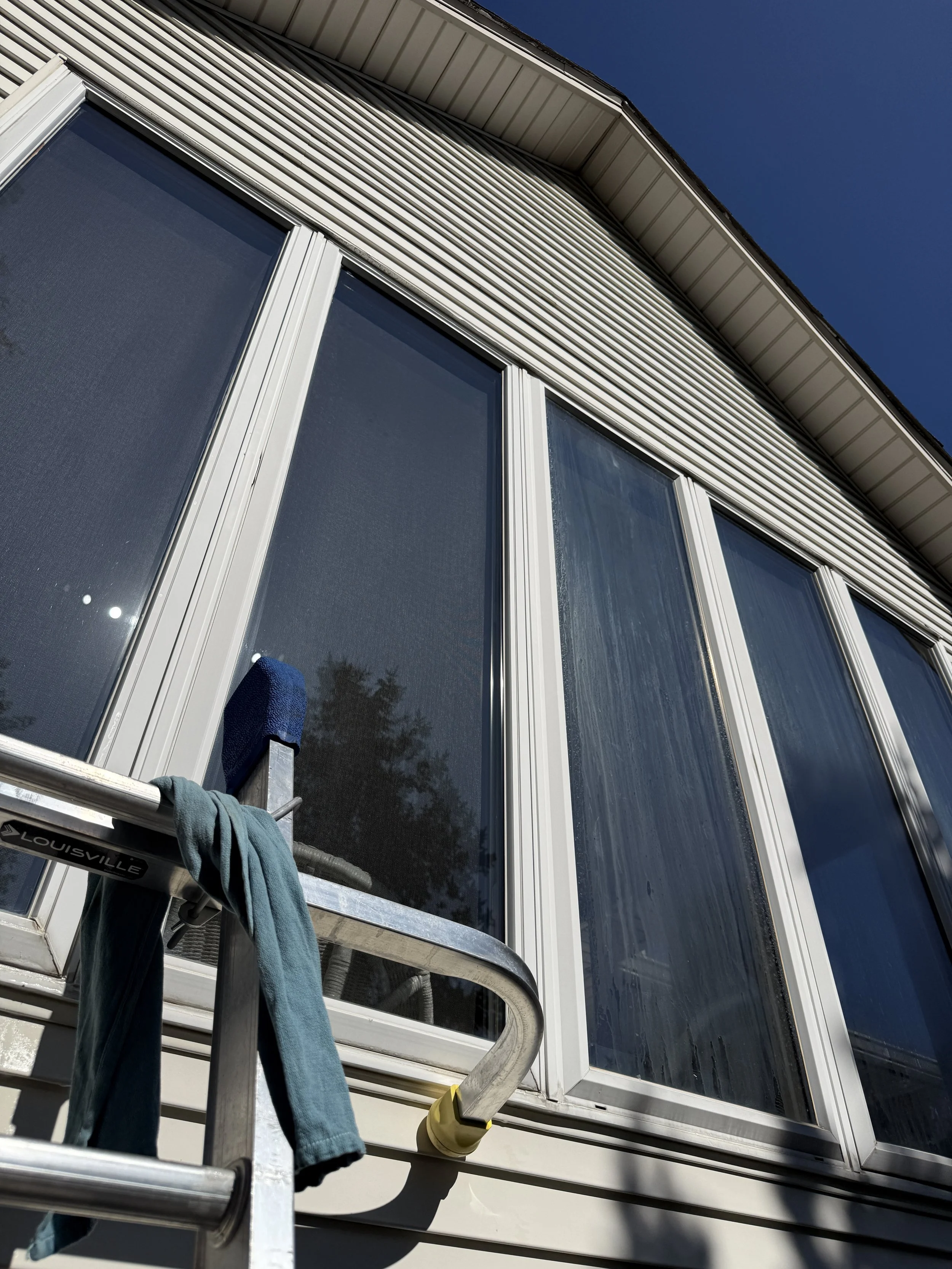 A close-up view of a house's large glass windows with a before and after cleaning of hard stains.