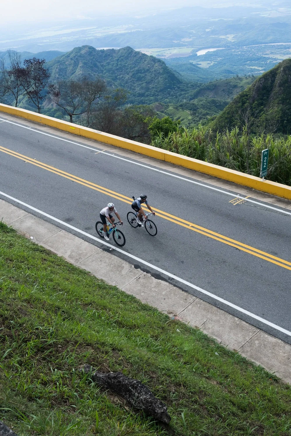 Two cyclists riding with a scenic mountain landscape, Into Coffee Heartlands