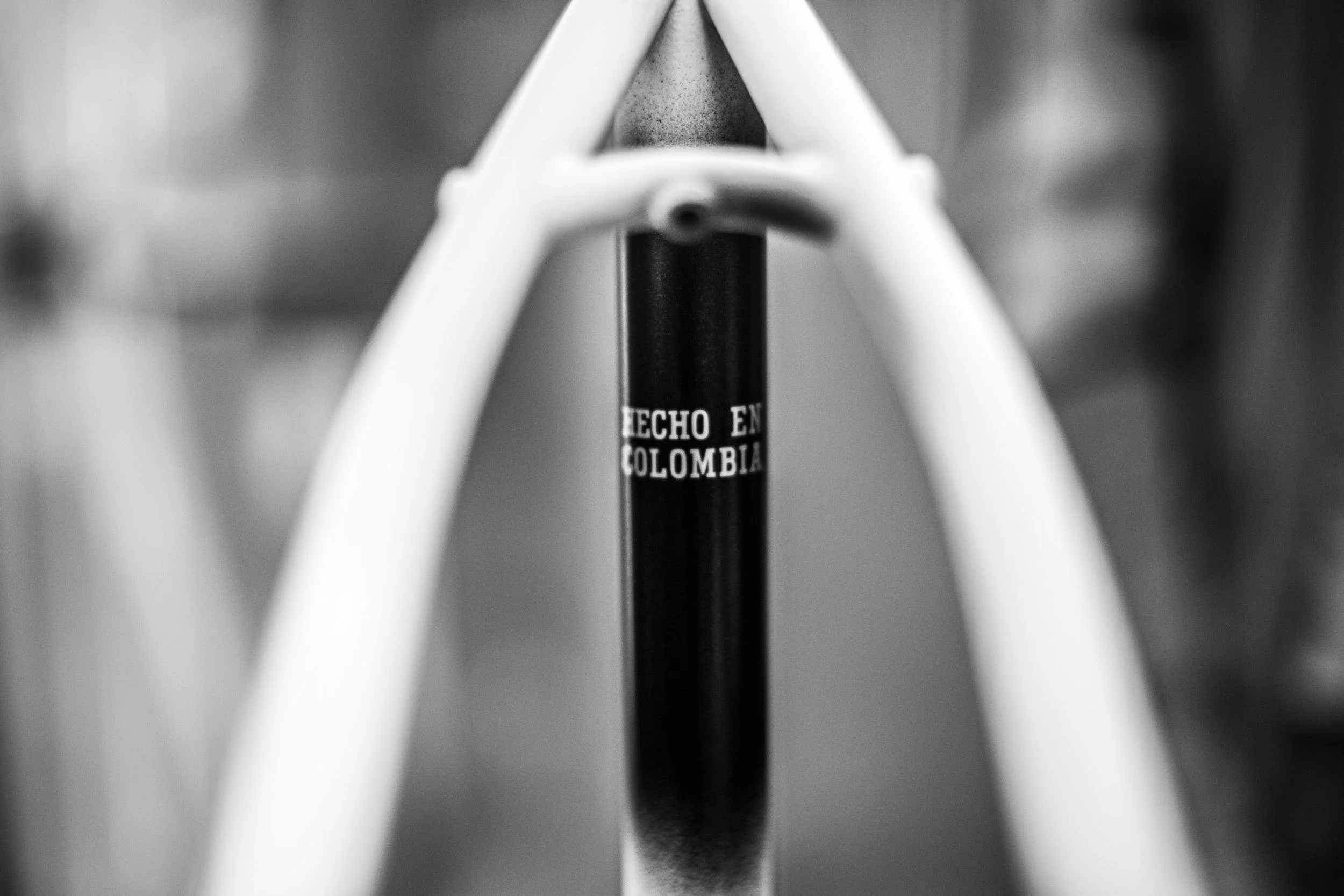 A black and white close-up photograph of the seat frame of a bicycle, with the label 'Hecho en Colombia' visible on the seat post.
