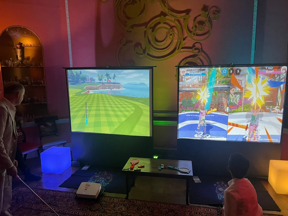 Guests playing on two large gaming screens