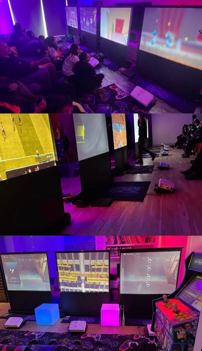 Screens and gamers in a gaming lounge with multiple monitors and gaming equipment, surrounded by neon lighting.