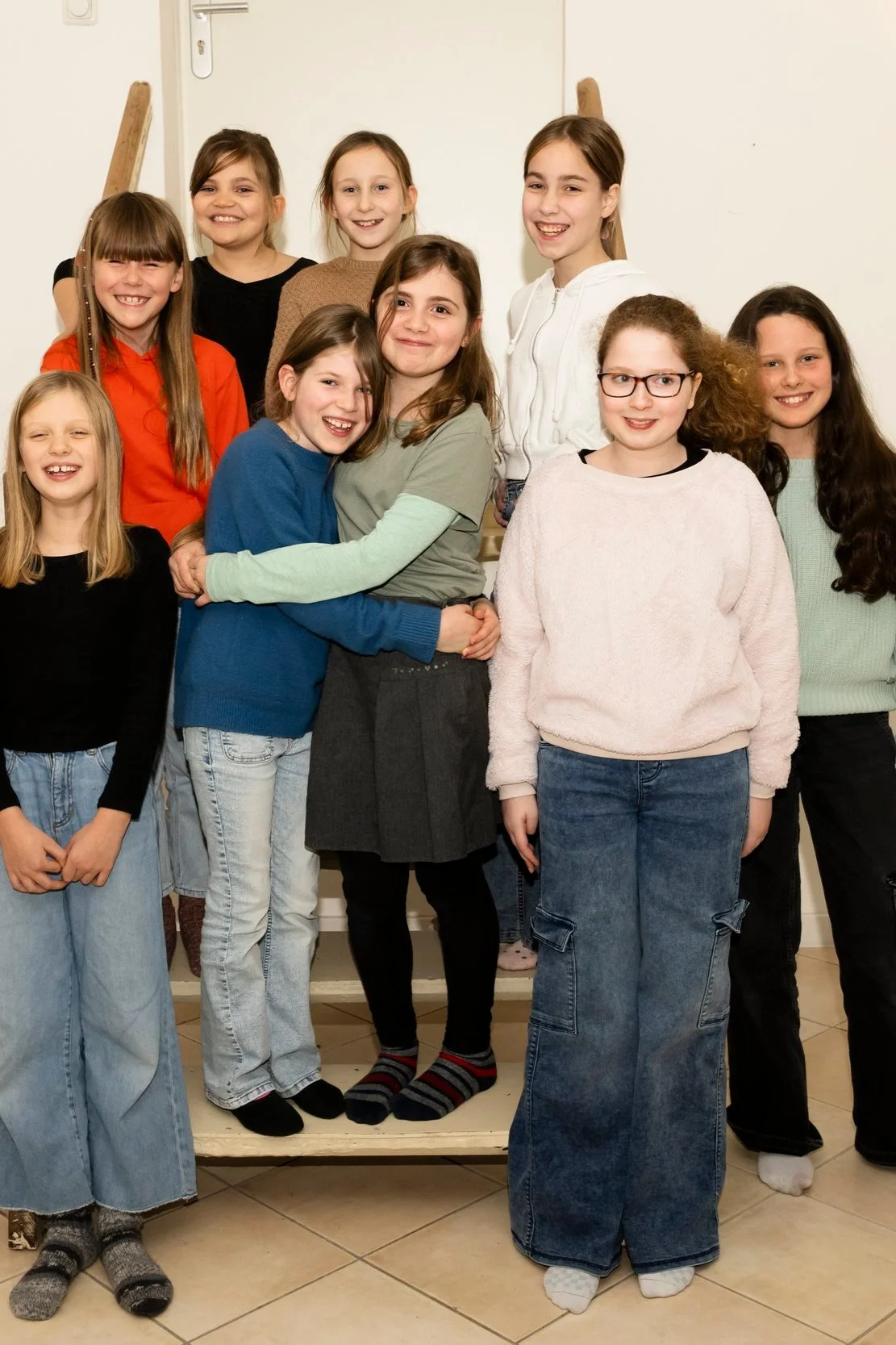 Gruppe von Kindern, hauptsächlich Mädchen, die zusammen lächeln und posieren.