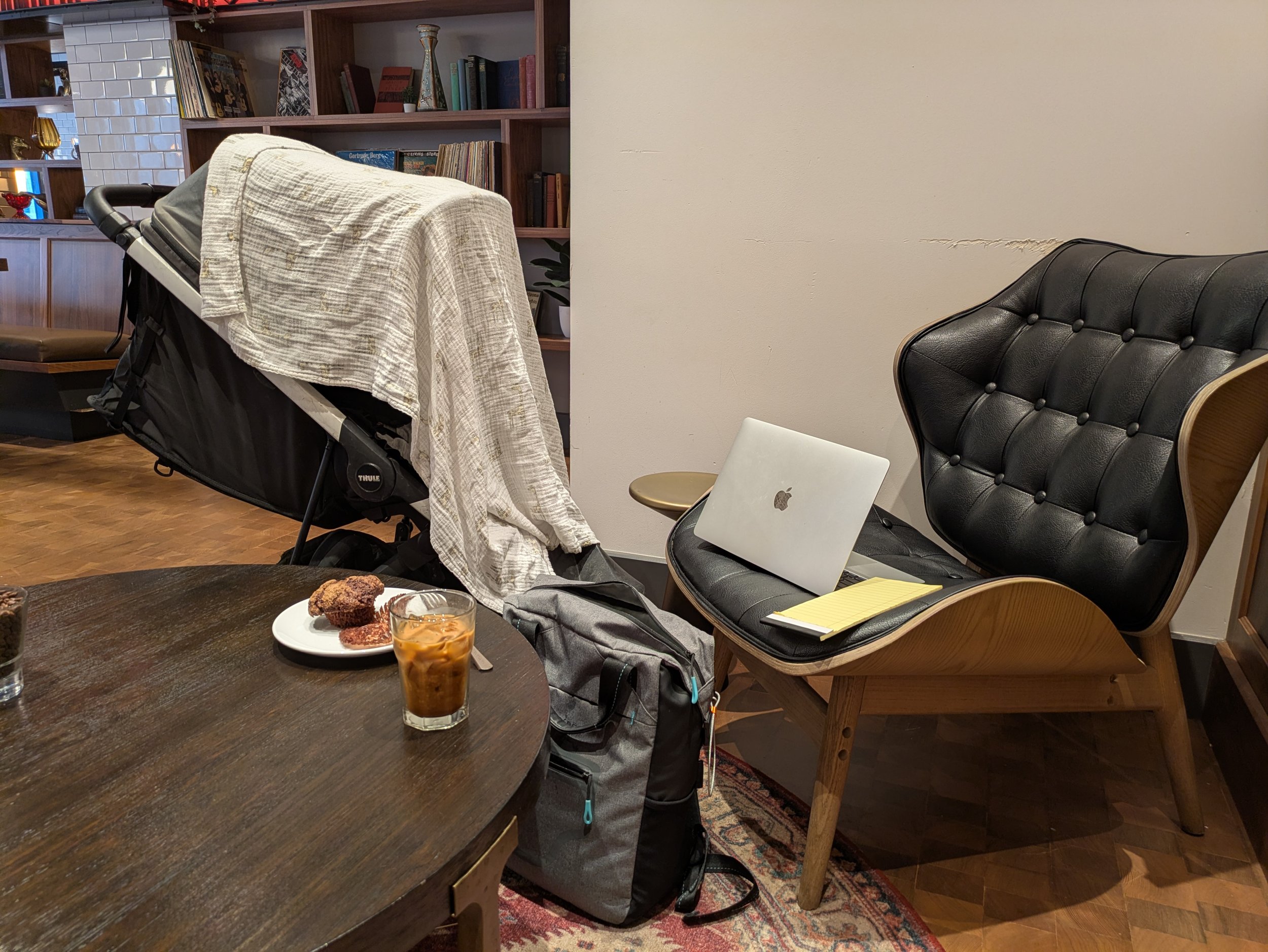 A cozy cafe corner with a working mom's laptop and iced coffee