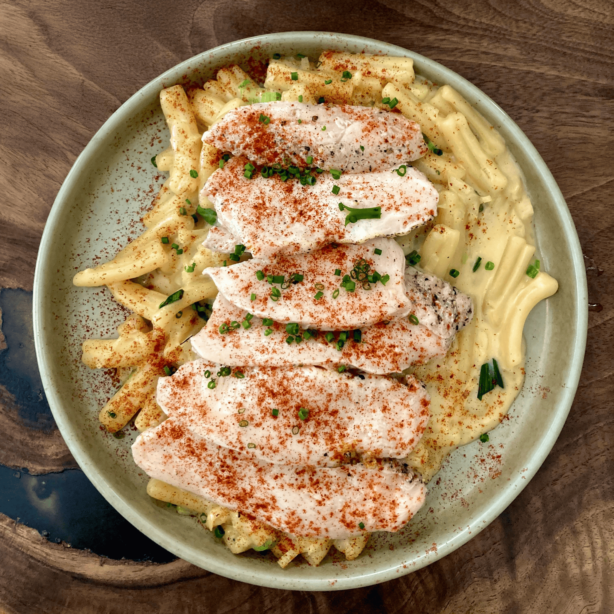 Assiette de pâtes nappées de sauce crémeuse à la moutarde, avec lamelles de poulet, paprika et ciboulette