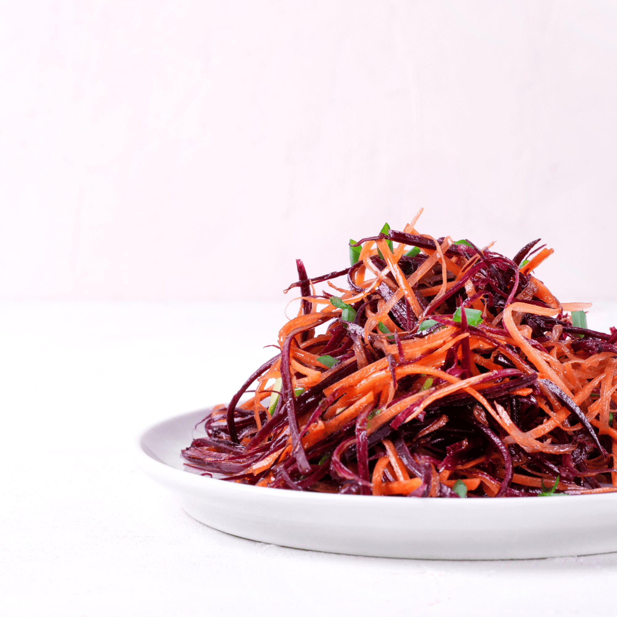 Assiette de salade arc-en-ciel à base de carottes et betteraves râpées, servie avec une vinaigrette citron-miel