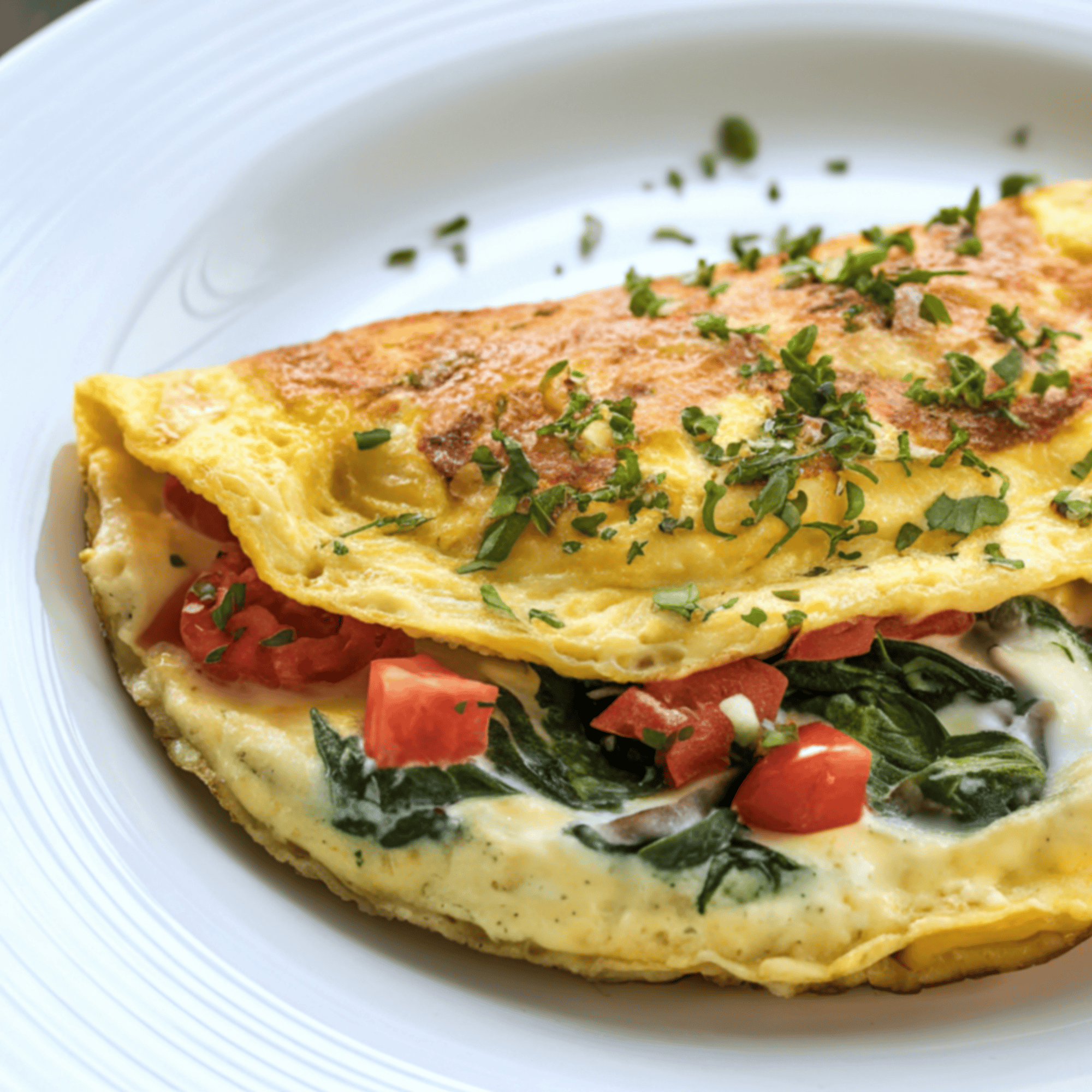 Omelette moelleuse garnie d’épinards, champignons et tomates, servie chaude avec du fromage frais fondant