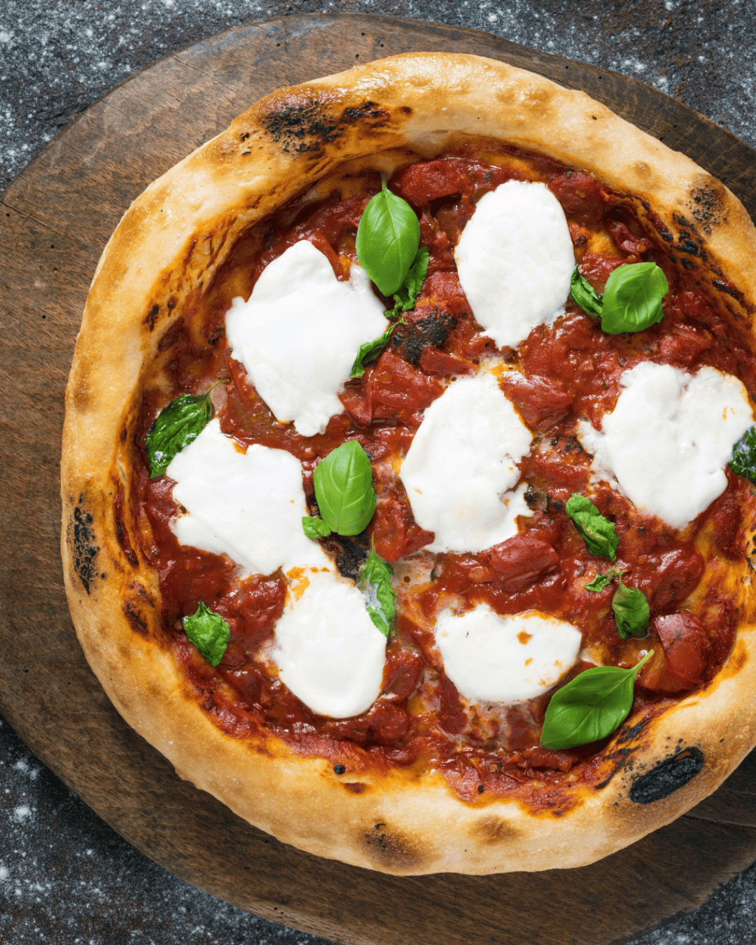 Pizza maison avec burrata fondante au centre, tomates cerises caramélisées, pâte fine croustillante, herbes fraîches et filet d’huile d’olive