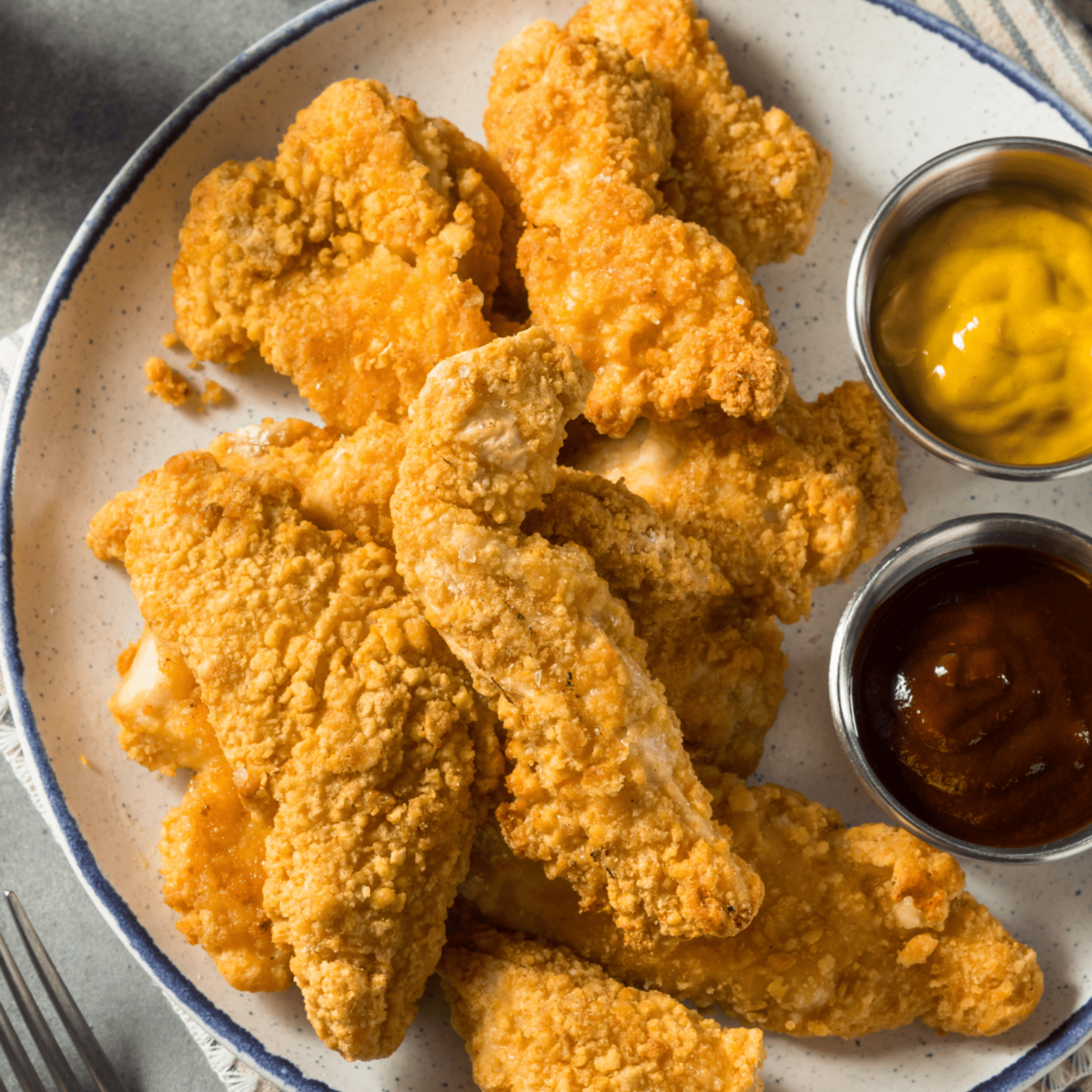 Assiette de tenders croustillants dorés au four, servis avec deux sauces maison
