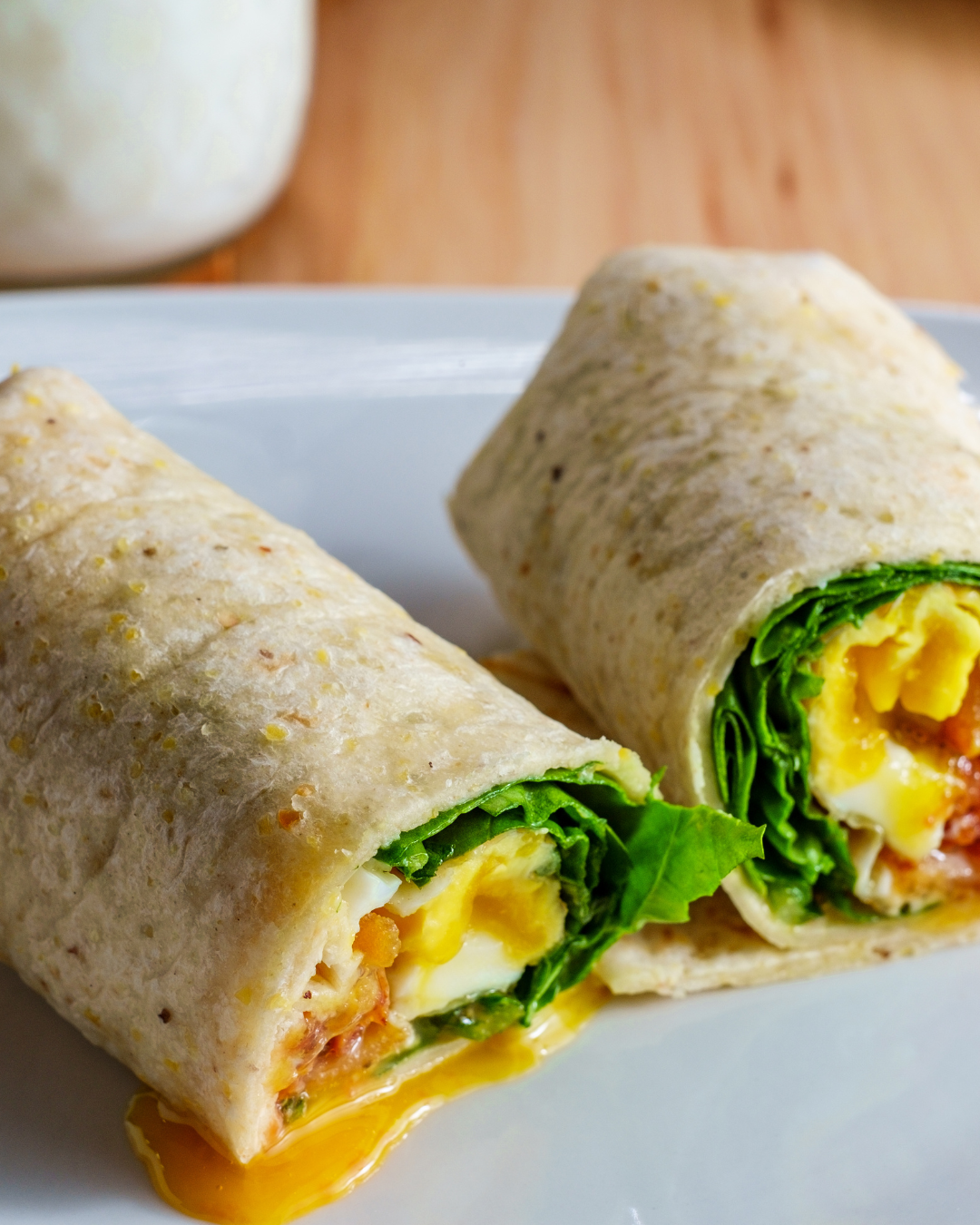 Wrap garni d’un œuf coulant, fromage frais, tomates confites et pousses de salade dans une tortilla, coupé en deux