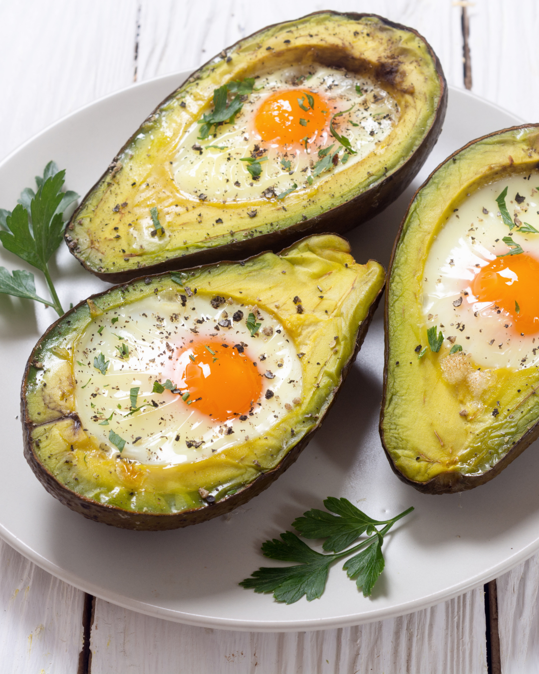 Demi-avocats rôtis au four avec œufs cuits au centre et herbes fraîches