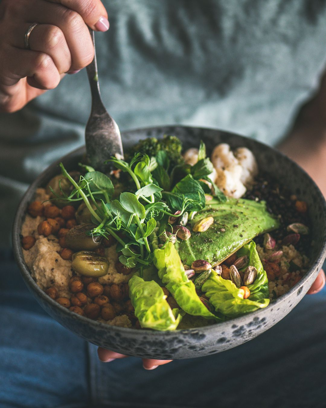 Bol de pois chiches rôtis au four, houmous et légumes verts croquants, servi avec graines et filet de citron sur fond rustique