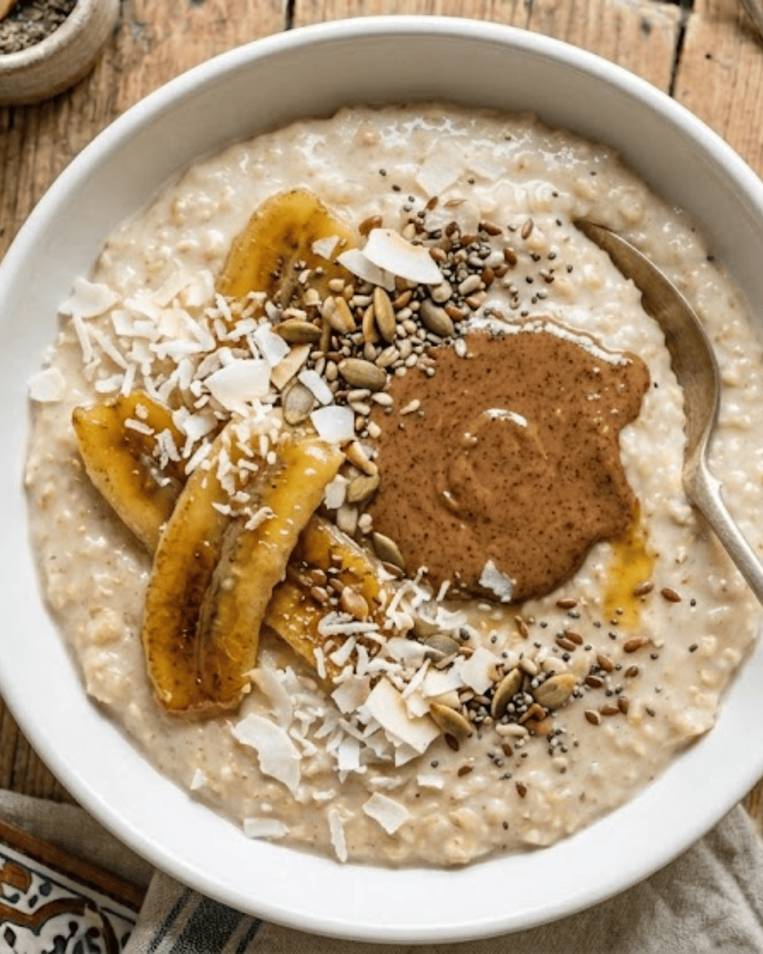 Porridge crémeux avec banane, purée d’amandes et graines dans un bol.