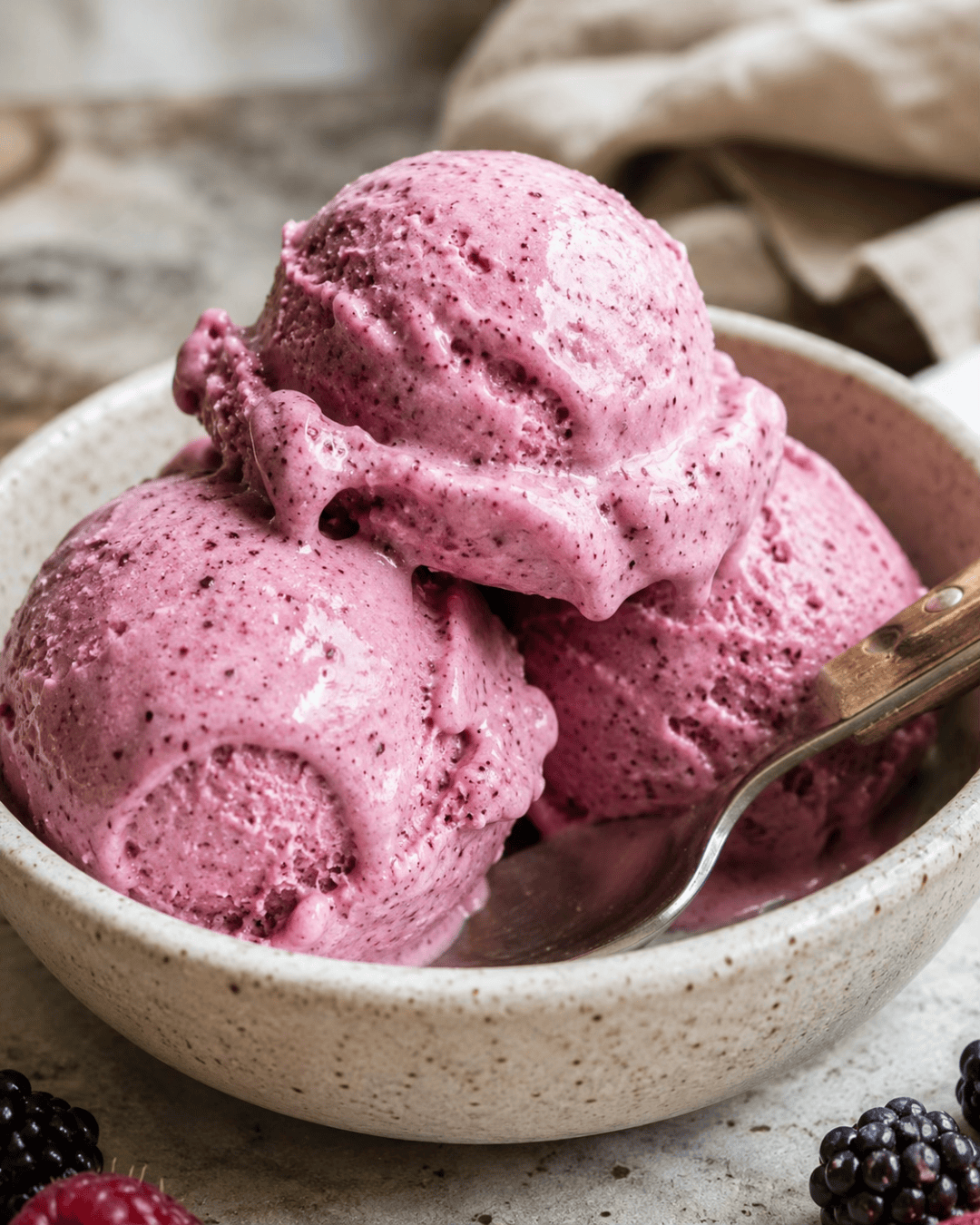 Glace crémeuse aux fruits rouges et lait de coco servie à la cuillère.