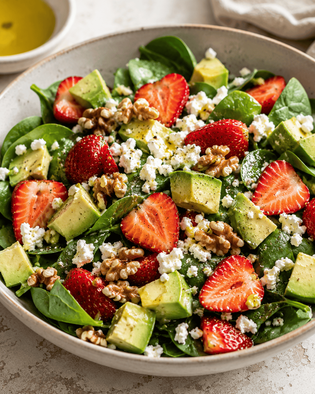 Salade de fraises, avocat et feta avec jeunes pousses et noix croquantes.