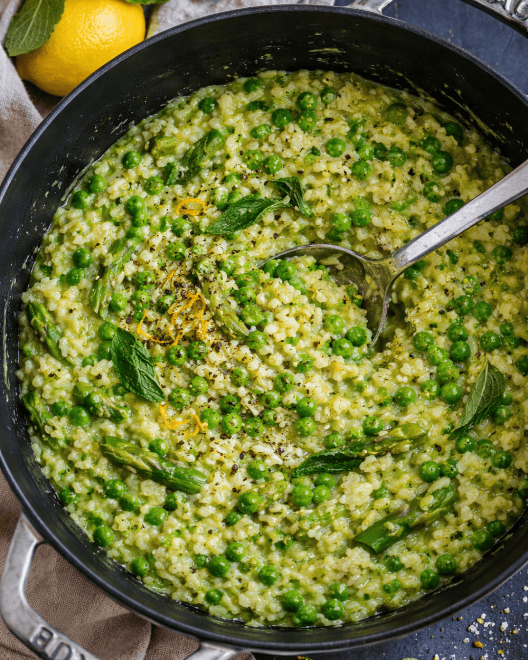 Risotto crémeux aux asperges, petits pois et citron dans une assiette.