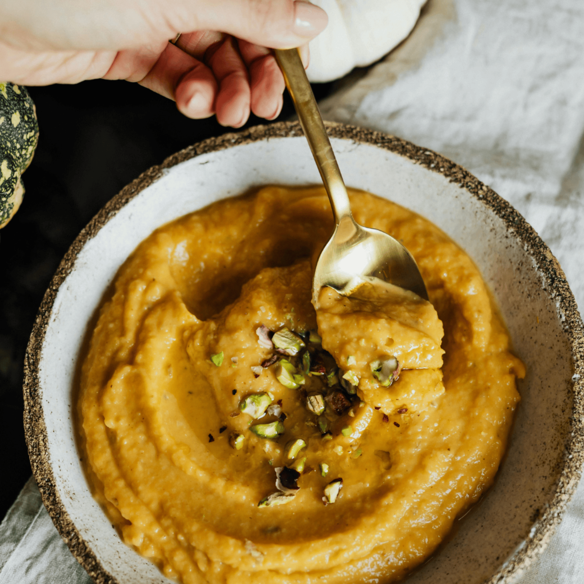 Bol de velouté de courge onctueux, garni de pistaches concassées