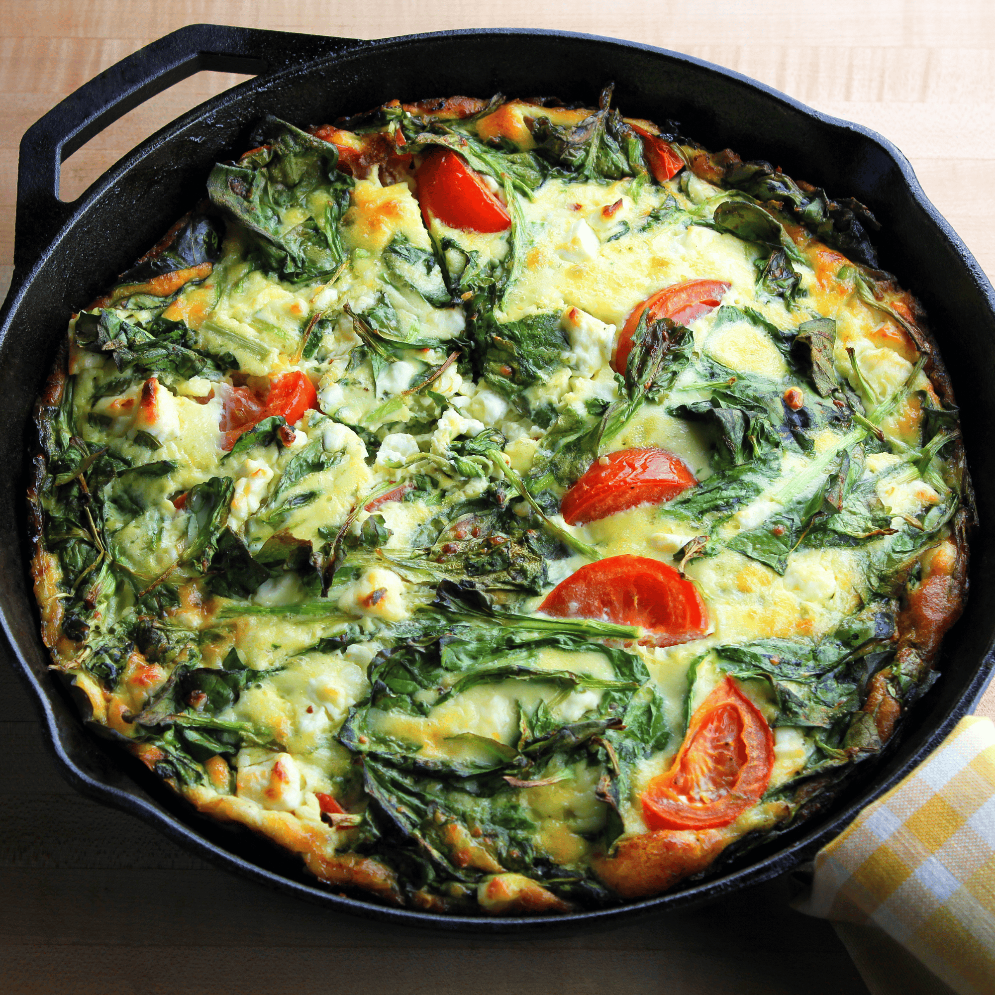 Frittata aux légumes verts, feta et tomates, servie en parts dans une assiette avec salade