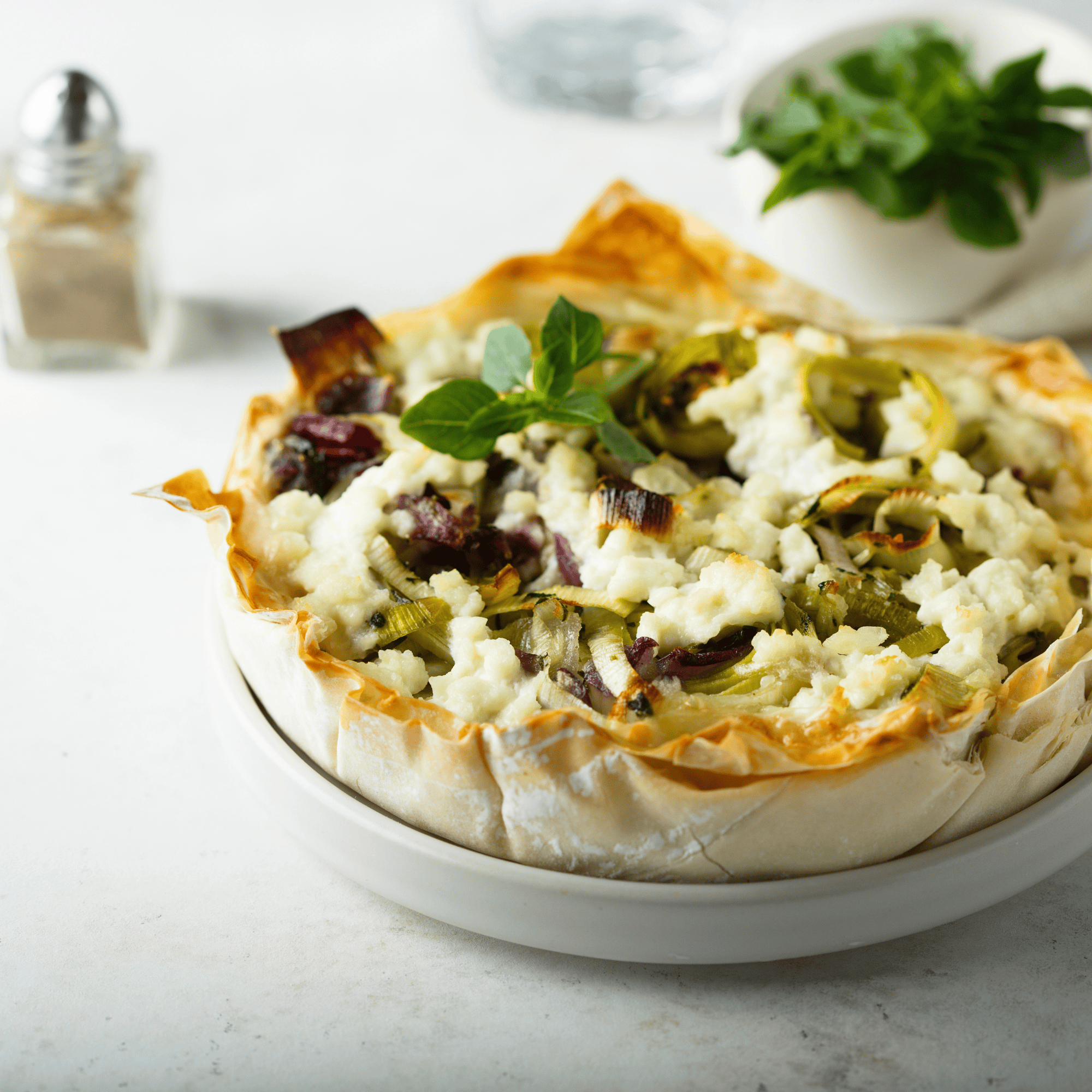 Tarte filo croustillante aux poireaux et feta, dorée au four, servie dans un moule rond