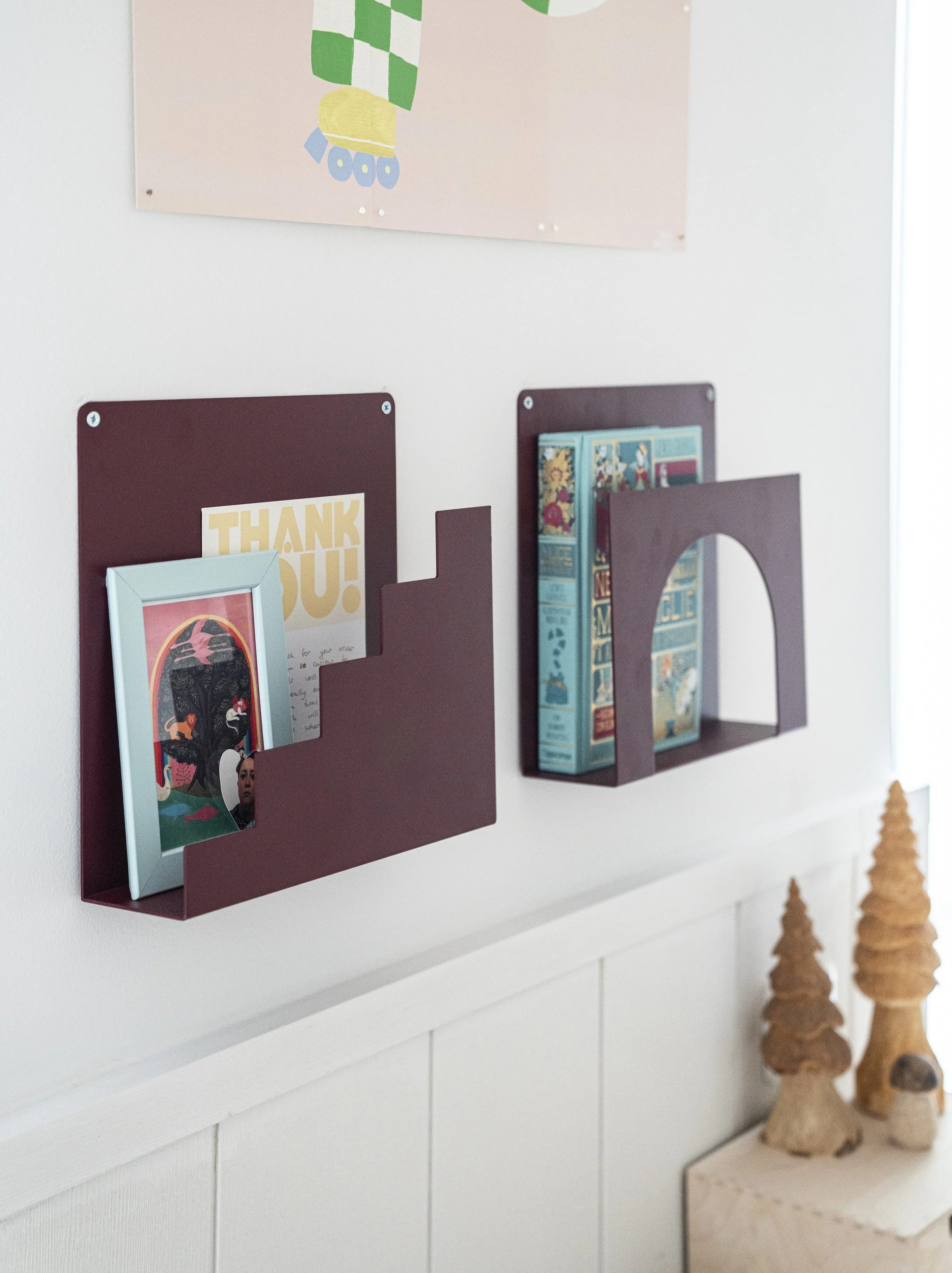 Librerie frontali a parete con libri per bambini sopra una boiserie bianca.