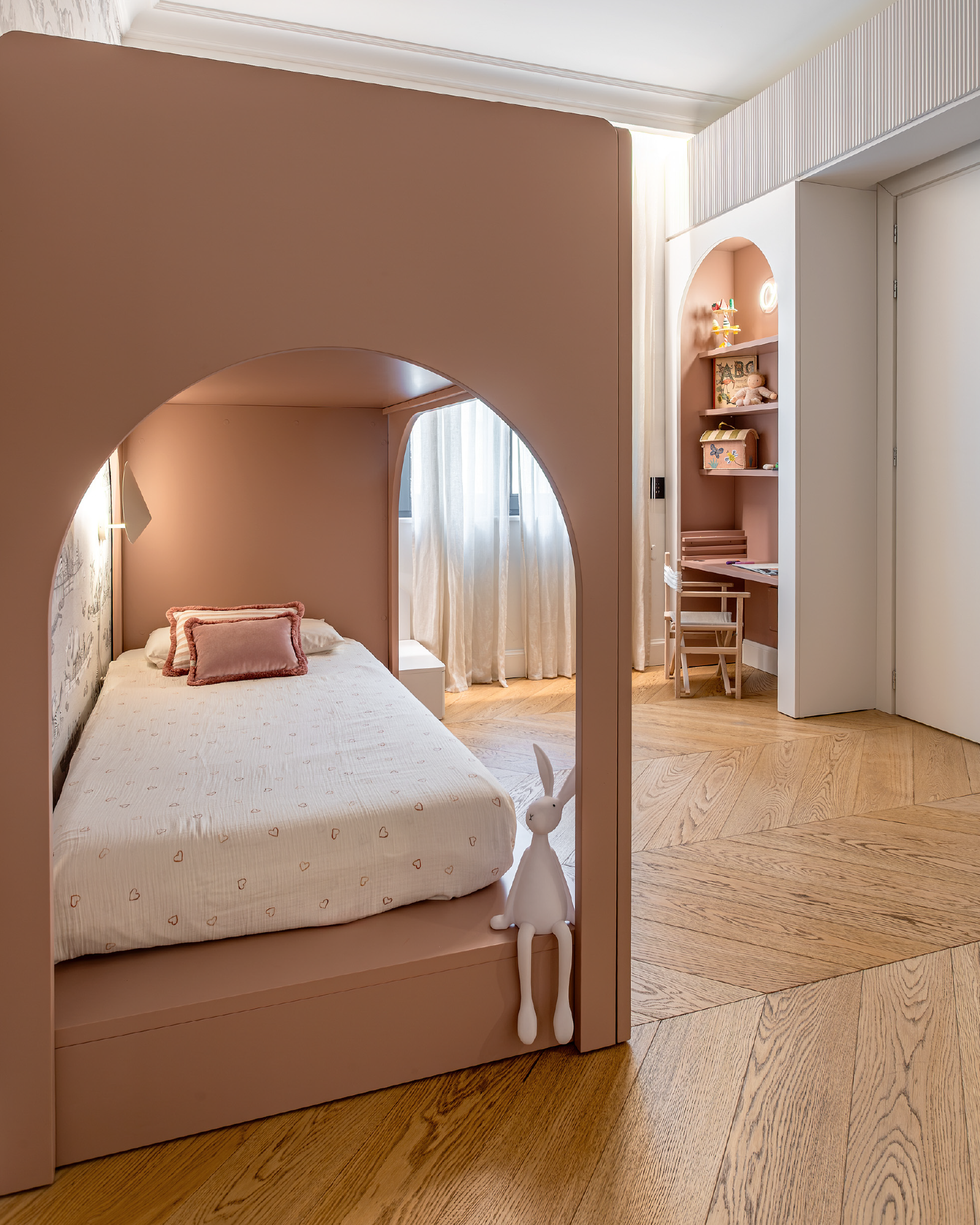 Vista attraverso un arco rosa verso la zona letto, con falegnameria su misura e camere comunicanti.