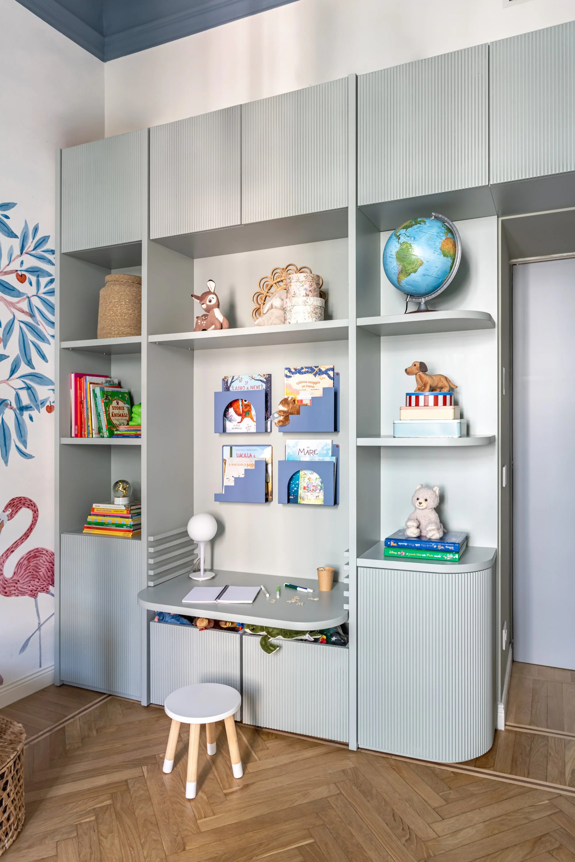 Parete studio su misura con scrivania, libreria, contenitori e mensole in tonalità verde salvia.