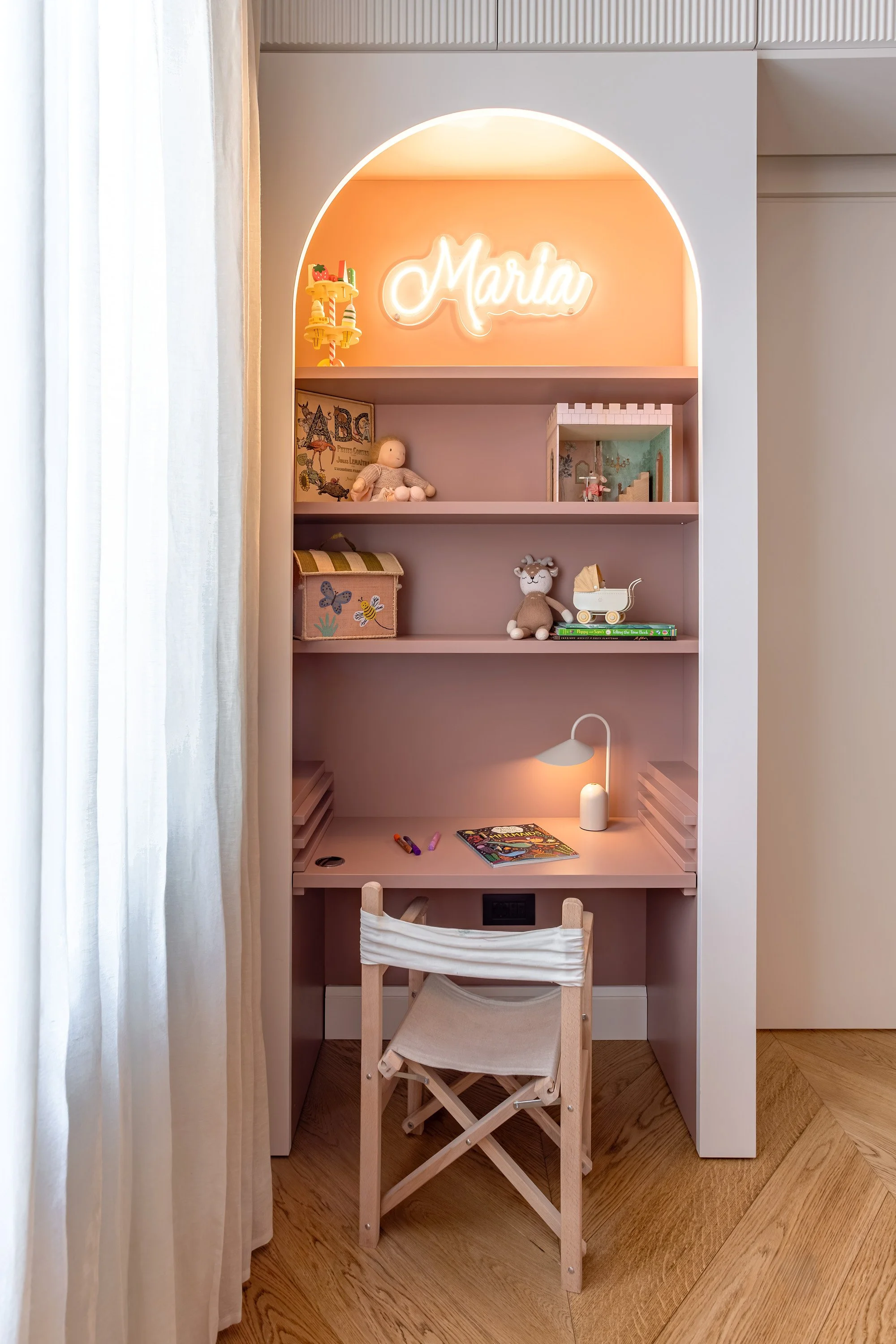 Nicchia studio rosa su misura con scrivania, mensole e contenimento integrato.