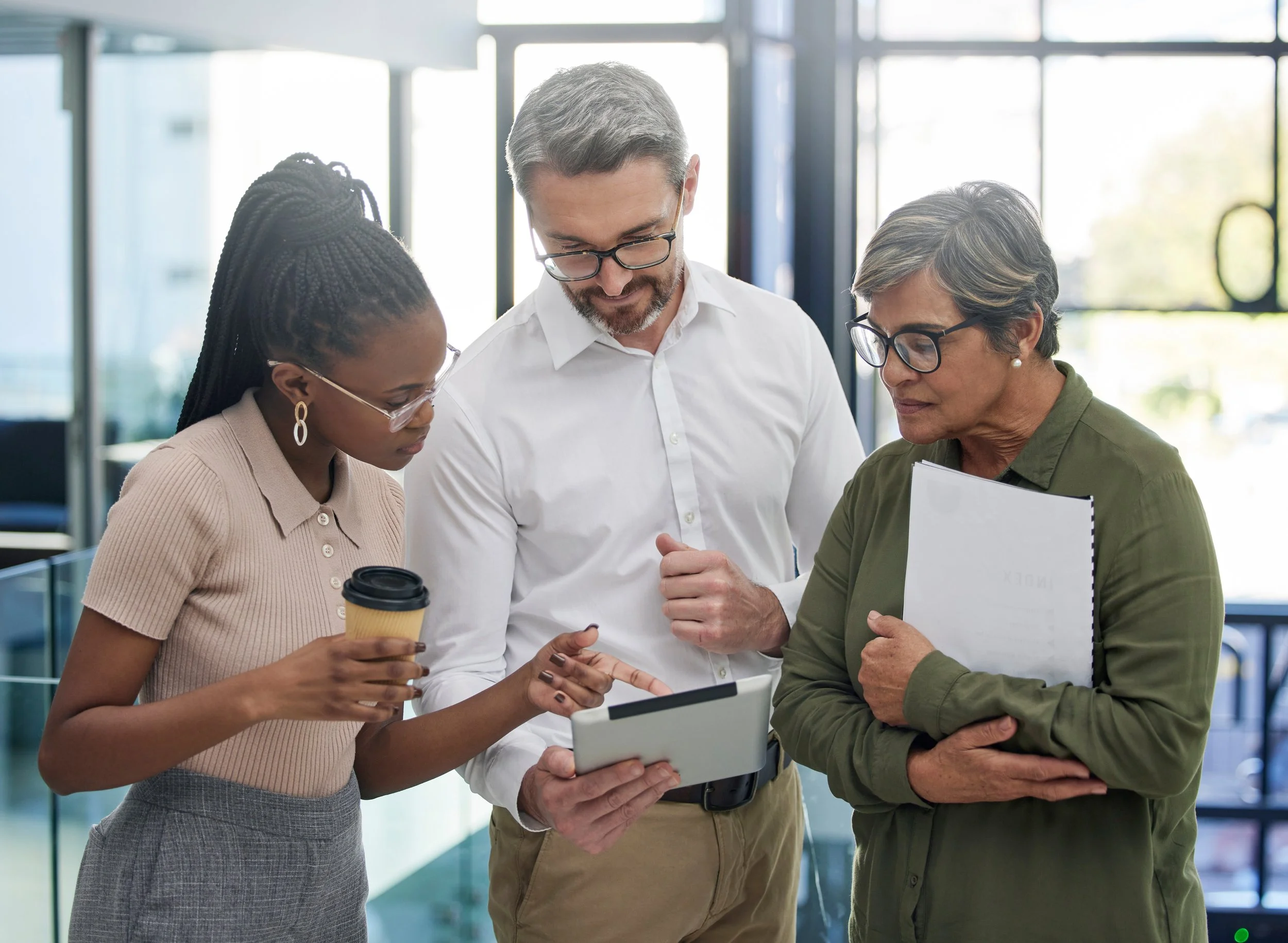 Three people looking at tablet together at work