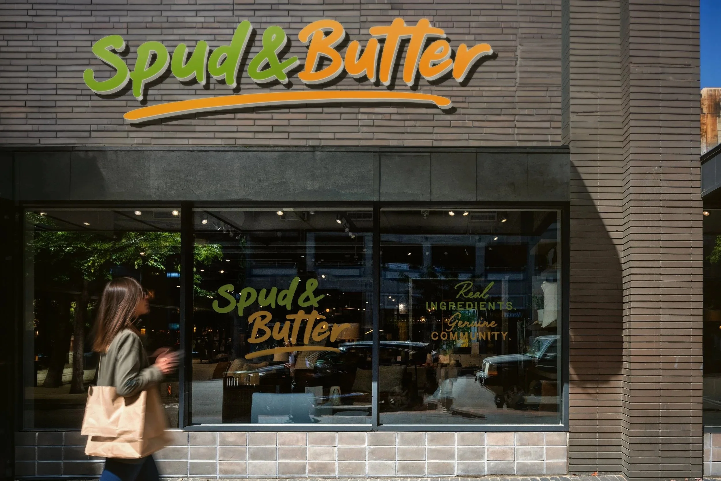 Storefront entrance concept for Spud & Butter fast casual restaurant in Tennessee. Front windows and a brick sidewalk in front.
