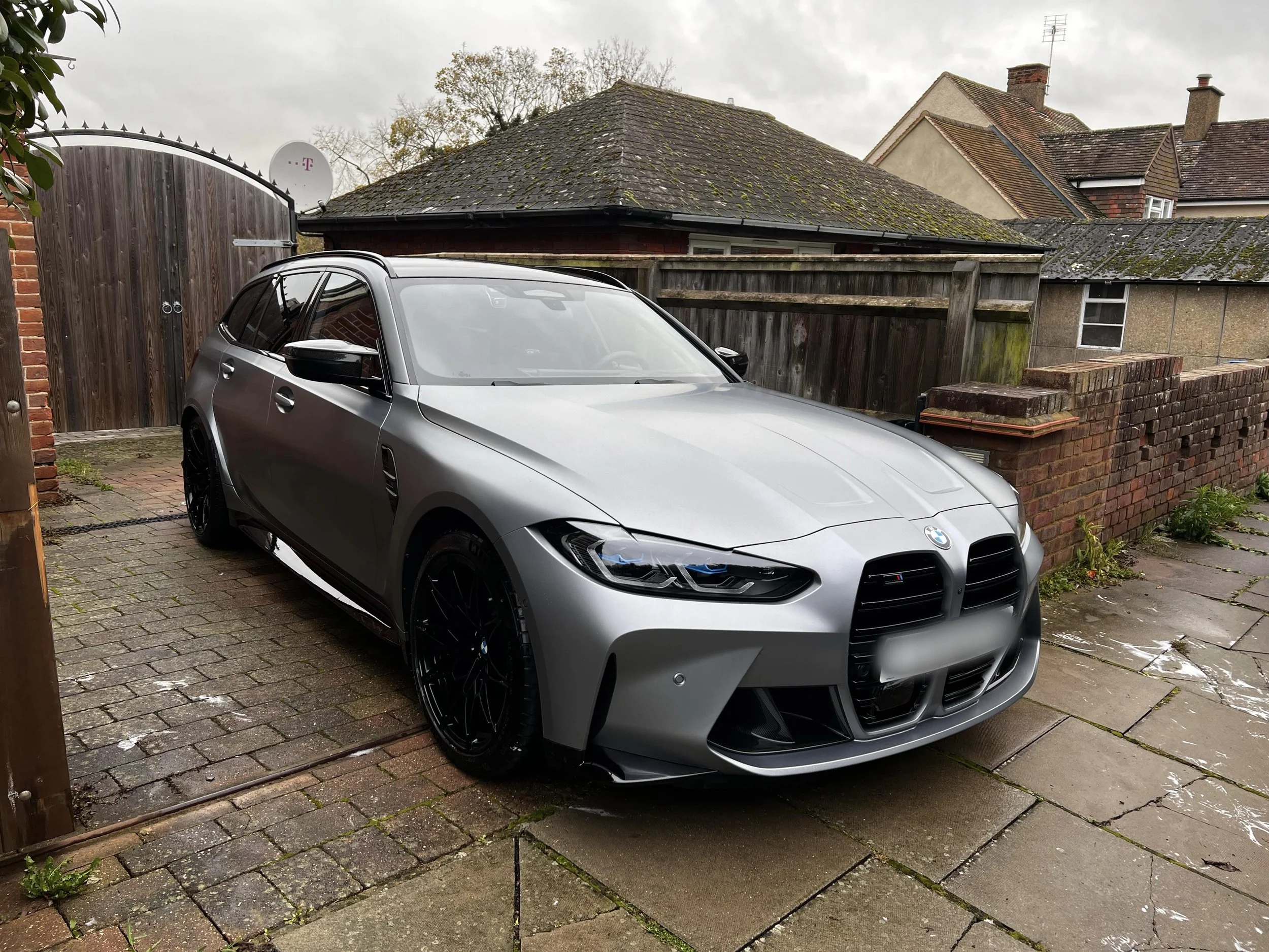 A silver BMW sports car parked in a driveway next to brick buildings.