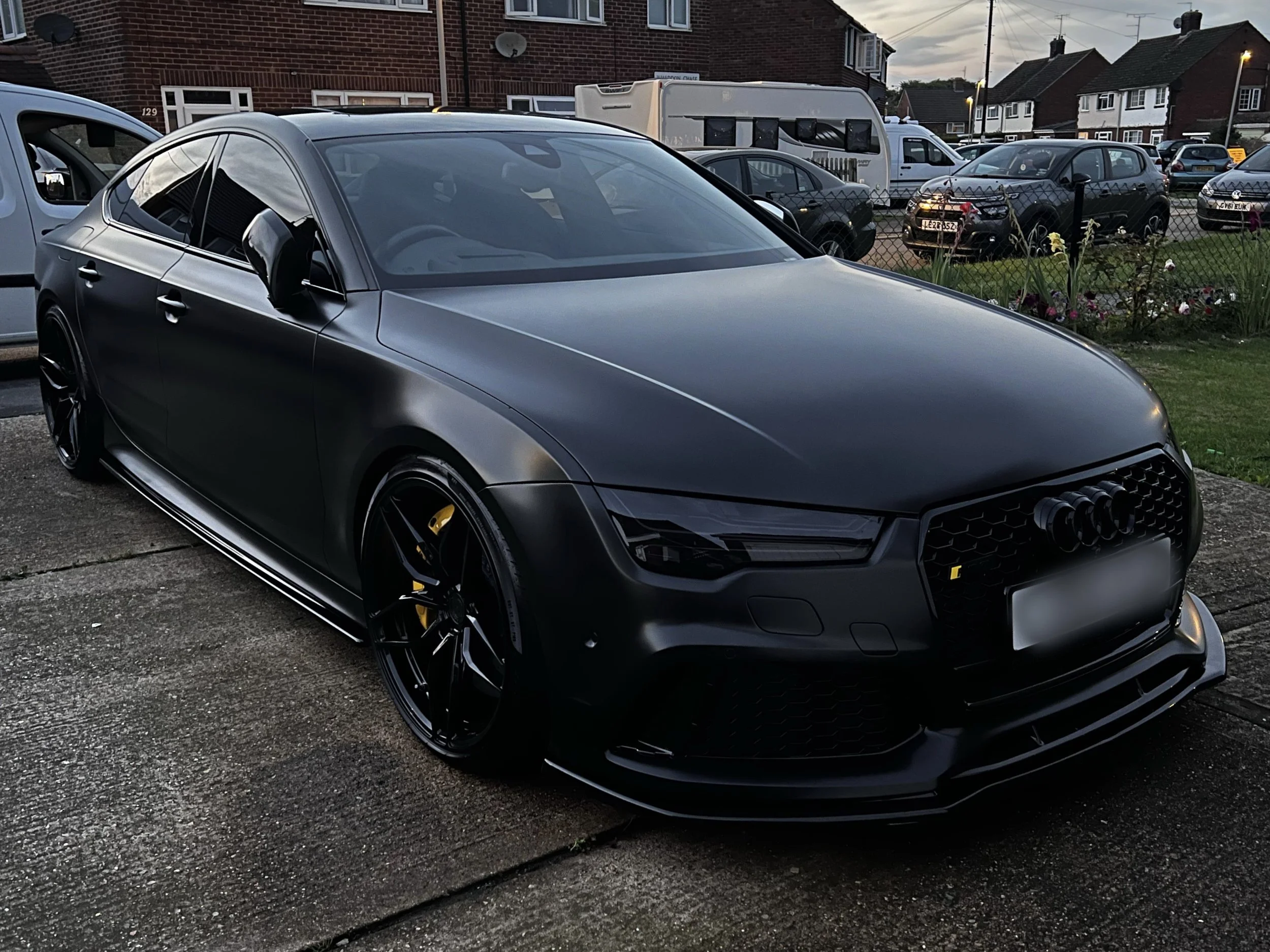Black Audi parked on a driveway in a residential neighborhood.