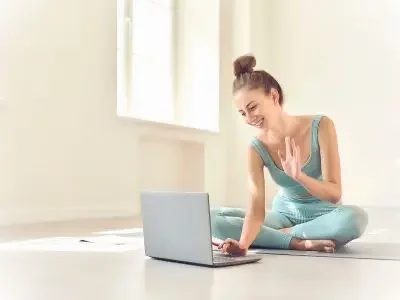 woman sitting on the floor waving to computer screen
