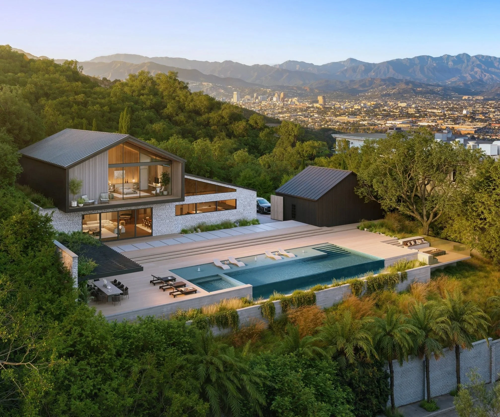 A modern hillside house with large glass windows, a swimming pool, outdoor lounge chairs, surrounded by lush trees and overlooking a city skyline with mountains in the background.