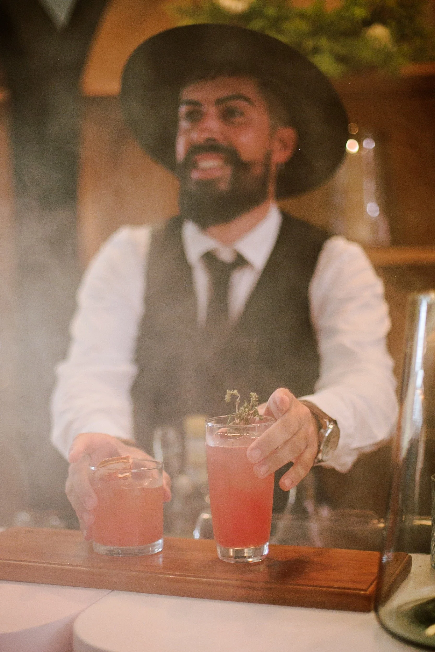 A bartender serving smoky mezcal cocktails at a wedding reception in Tulum.