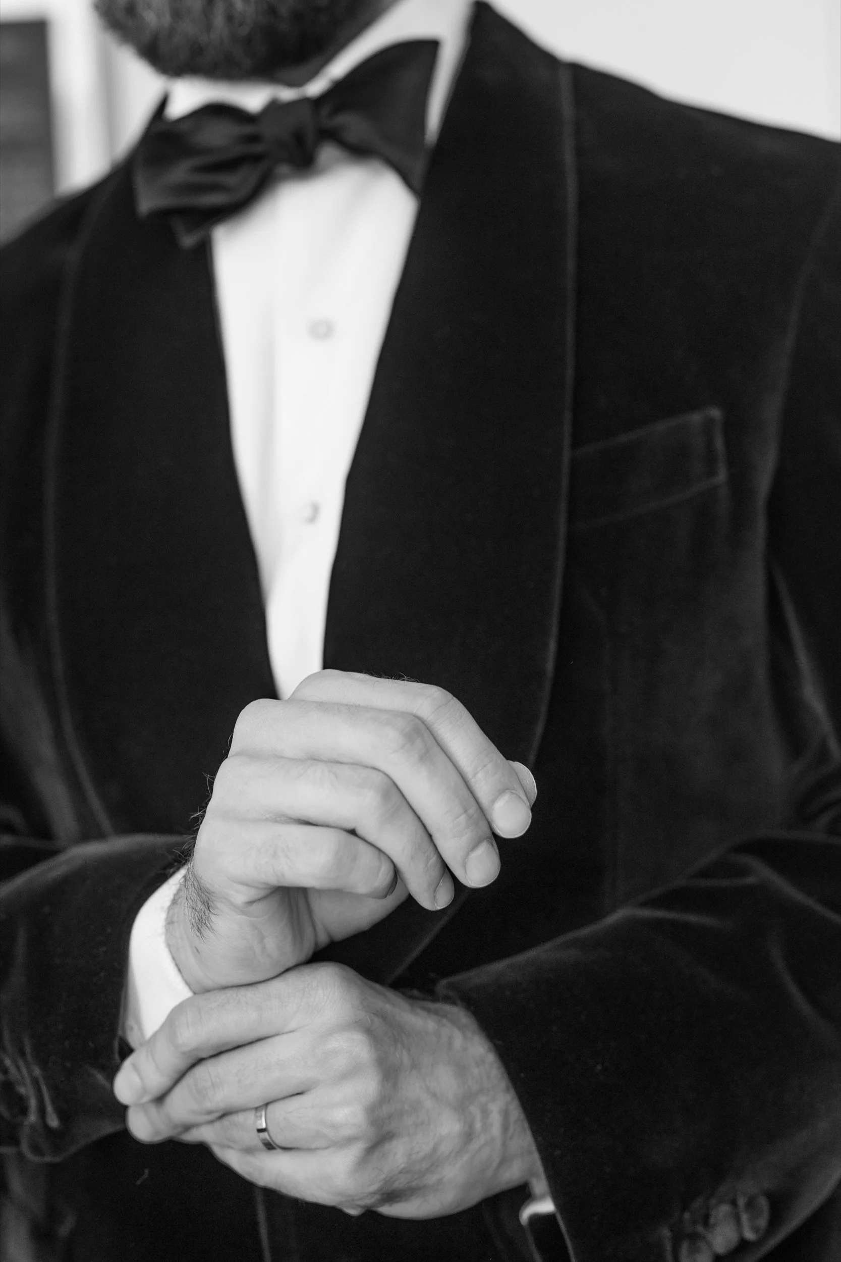A groom in his tuxedo adjusts his cufflinks