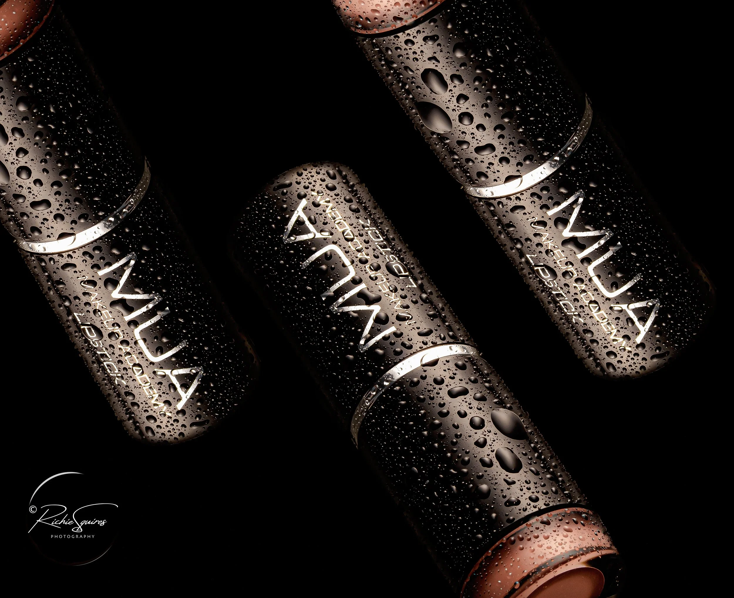 Three MUA lipsticks with water droplets on black background