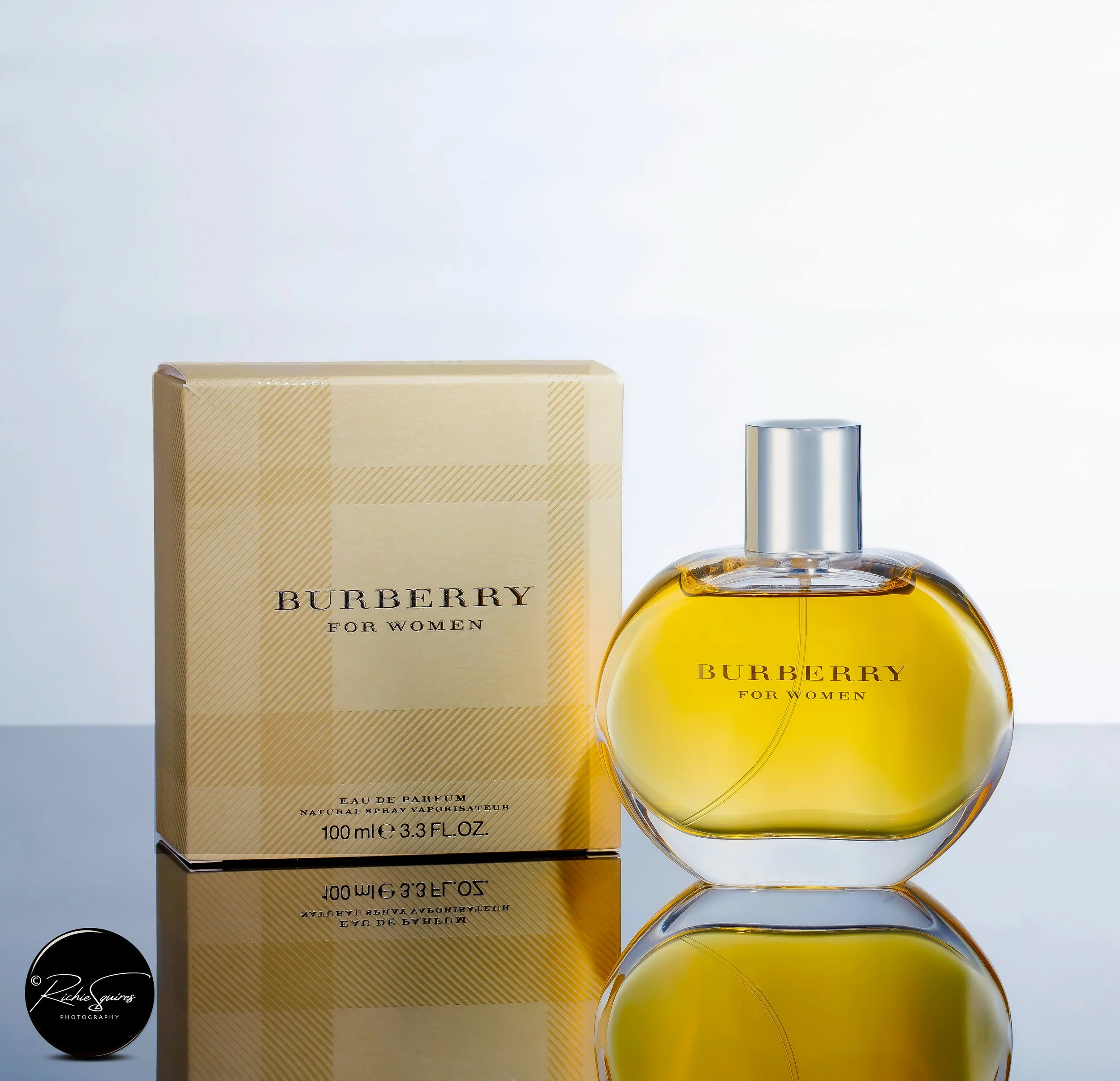 Burberry for Women perfume bottle and box on reflective surface.