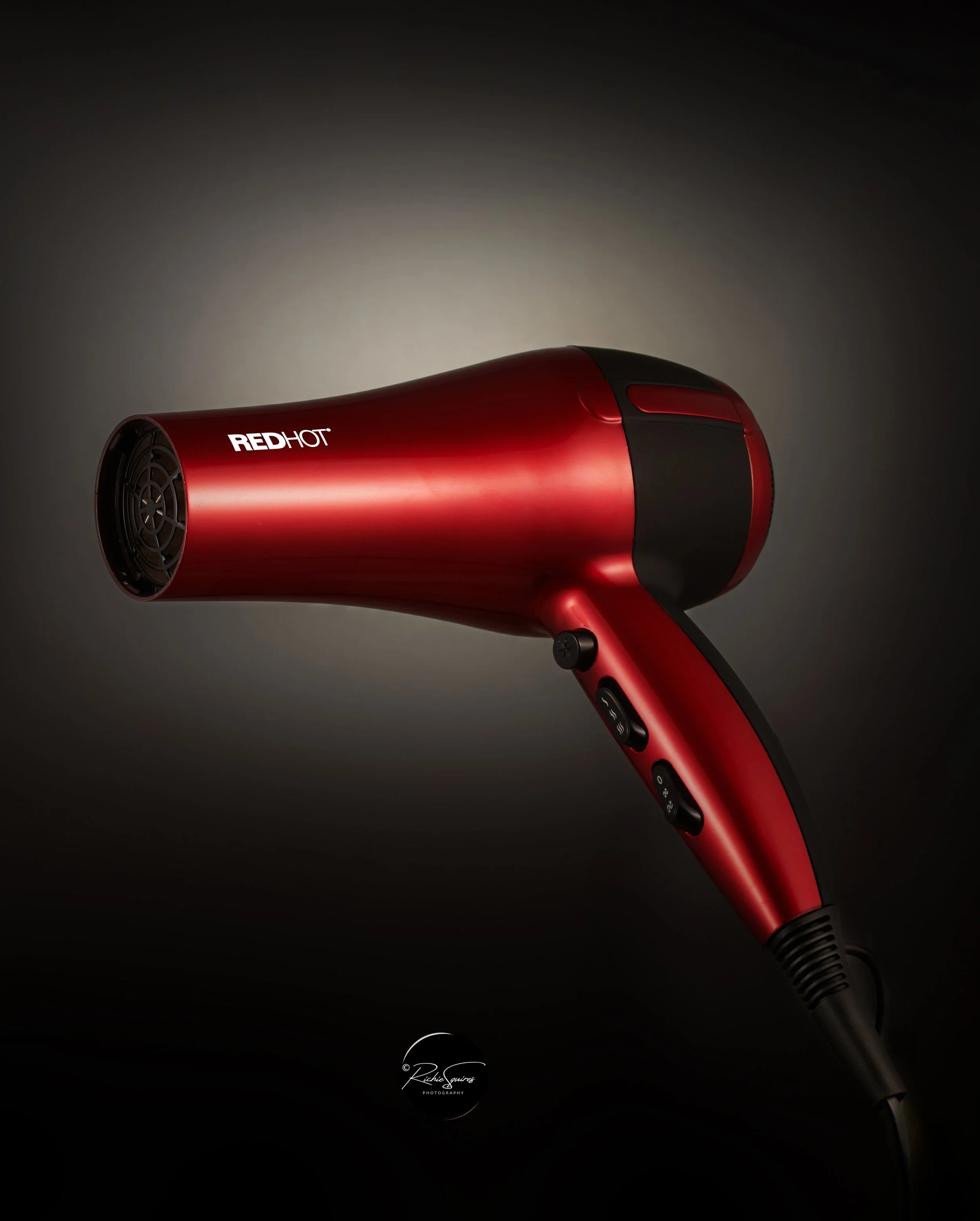 Red hairdryer with "RED HOT" branding against a dark background.