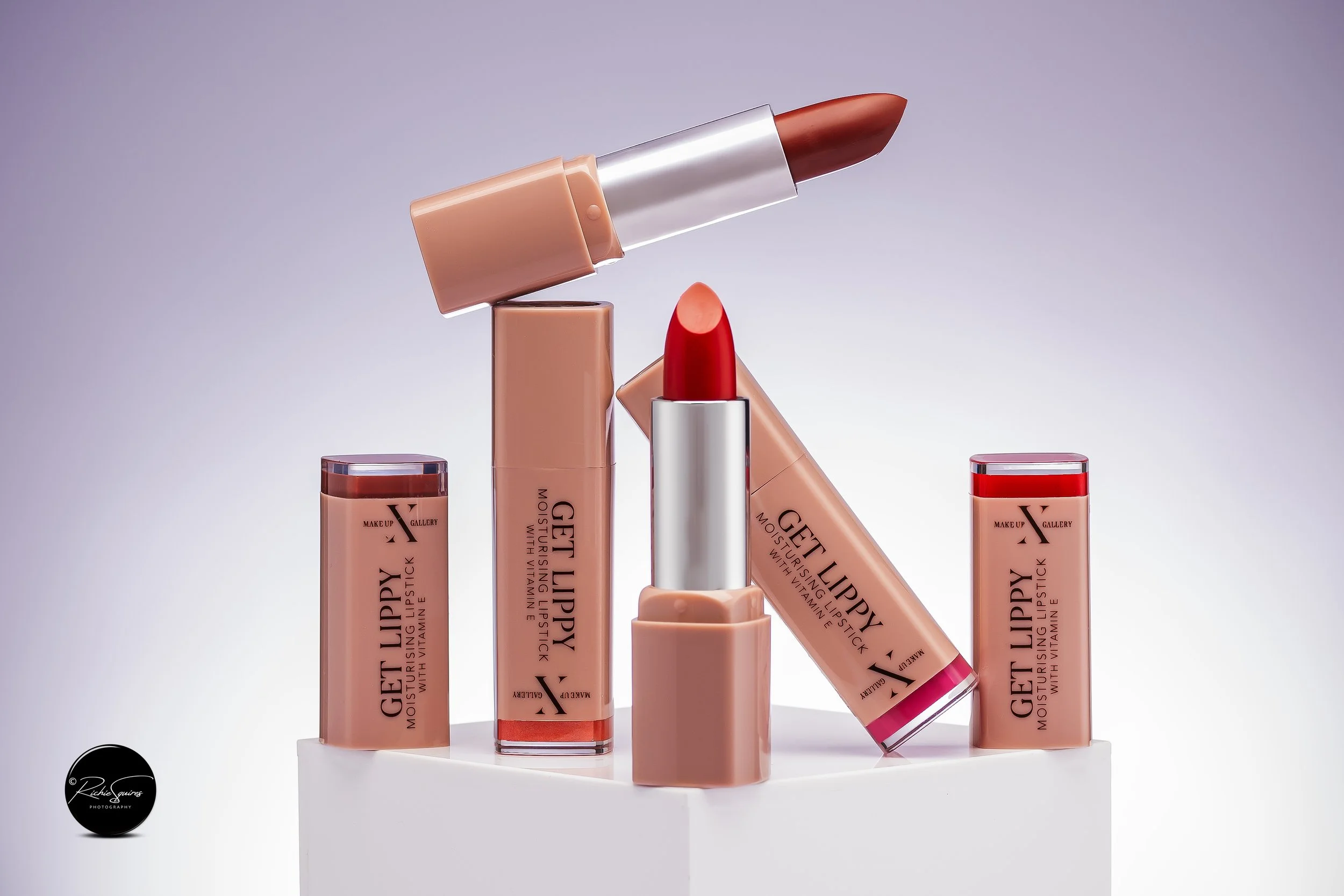 Assortment of lipsticks labeled 'Get Lippy Moisturising Lipstick with Vitamin E' in various red hues on a white surface.