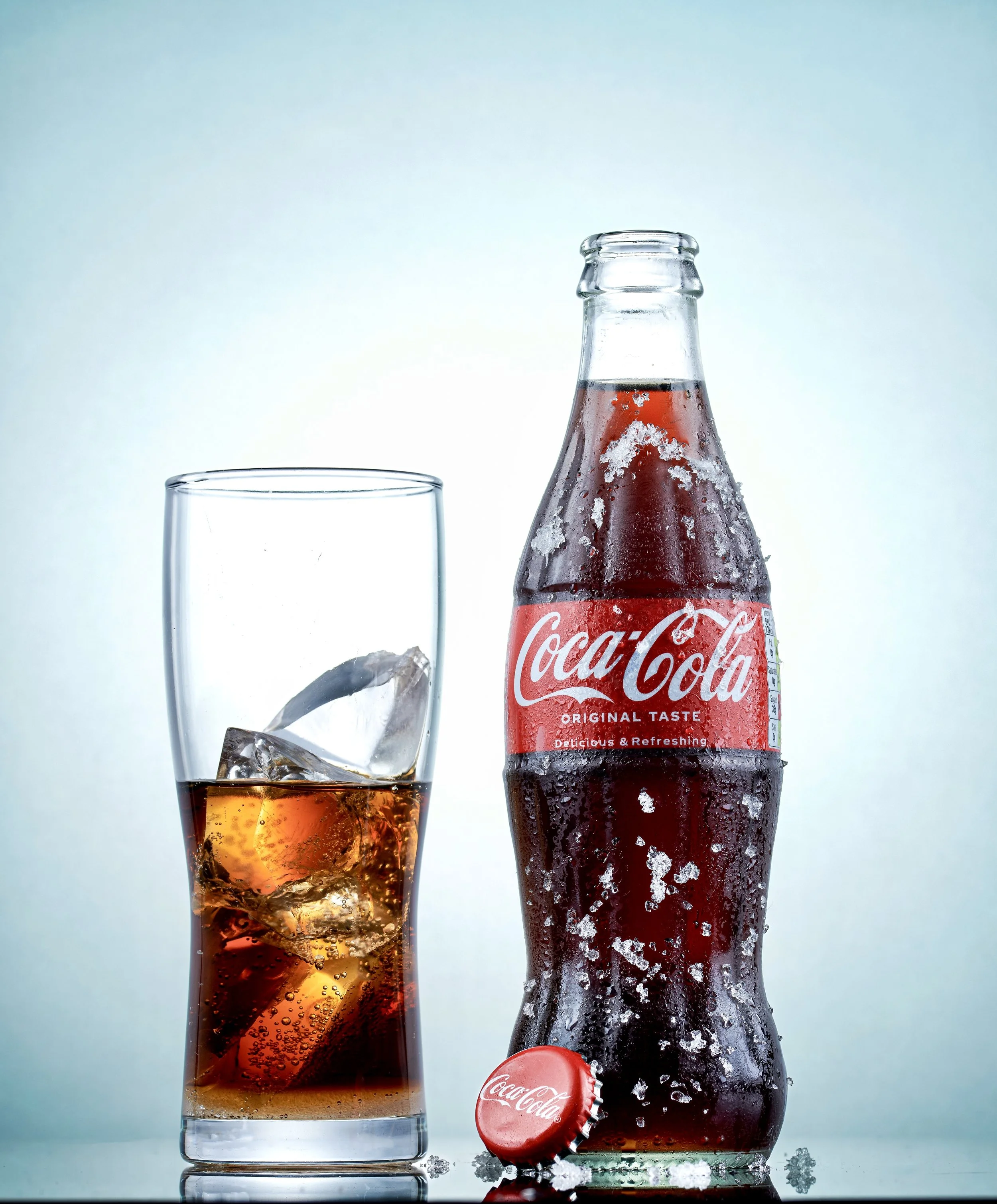 Glass of soda with ice and Coca-Cola bottle