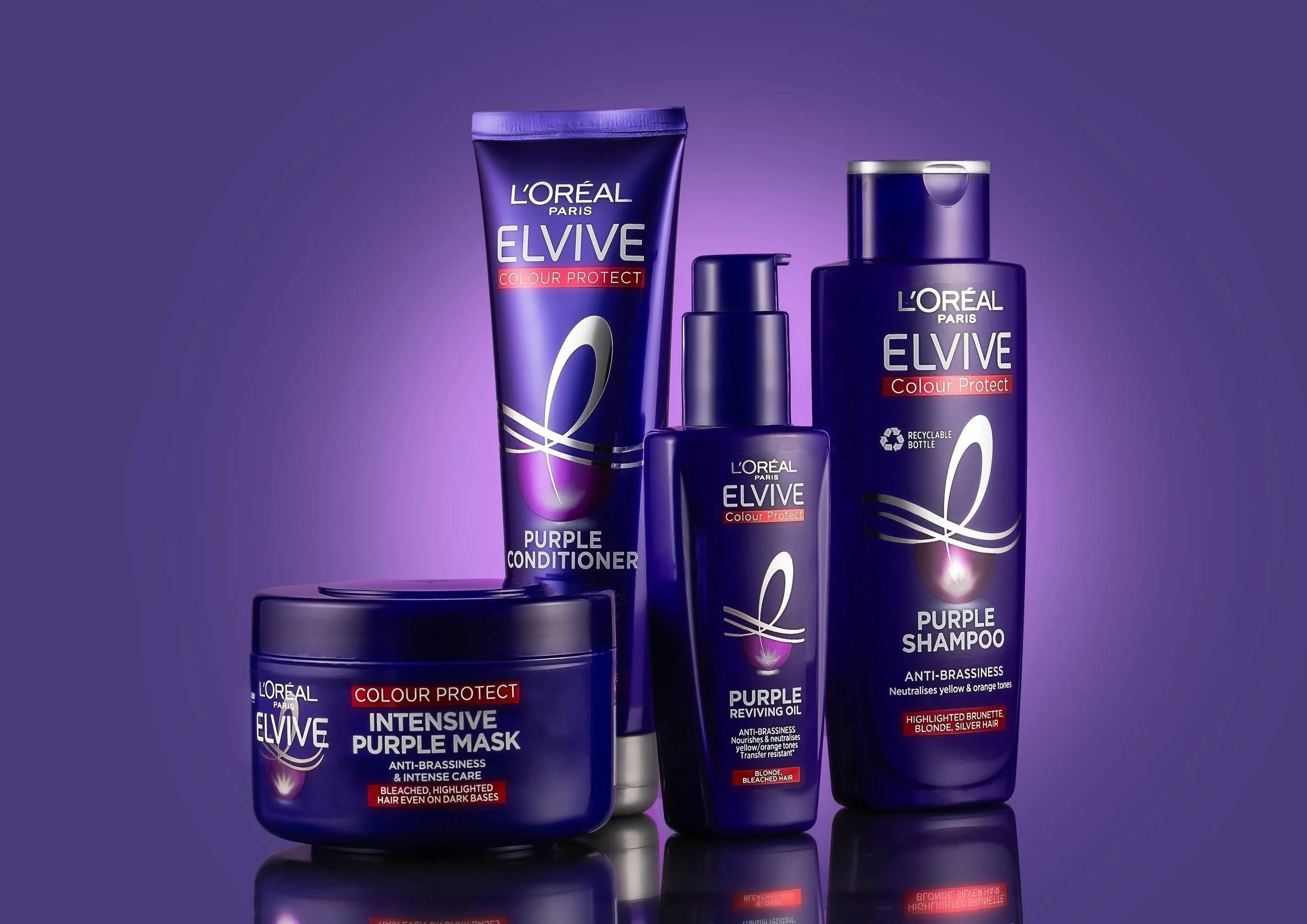 L'Oréal Paris Elvive Color Protect purple hair care products lineup including conditioner, shampoo, mask, and reviving oil with purple packaging on a purple background.