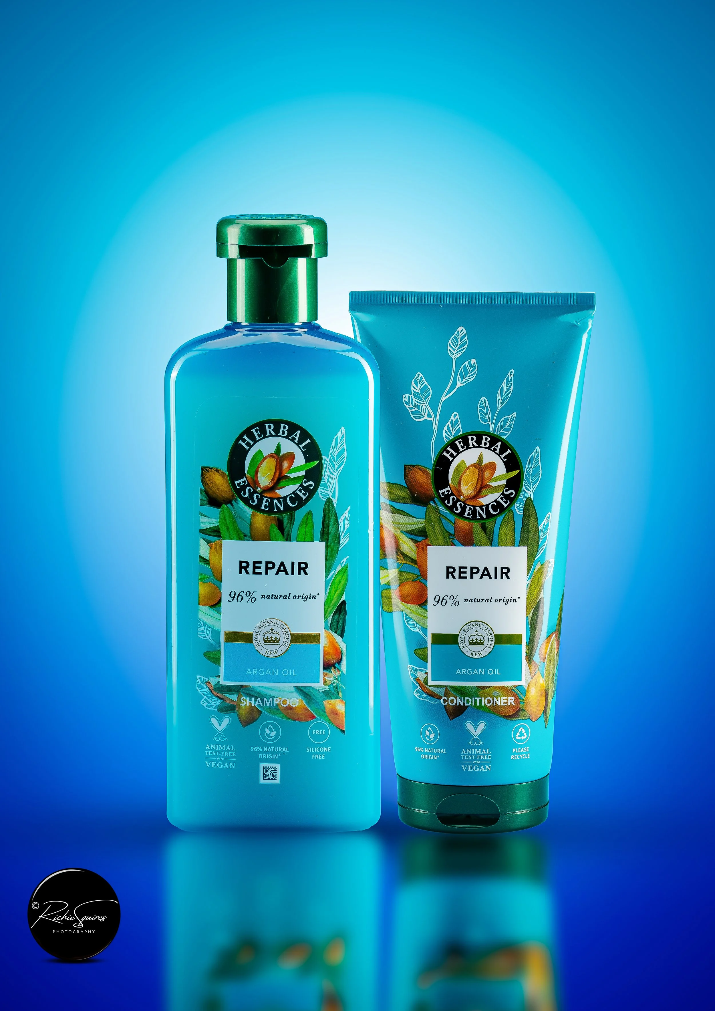 Herbal Essences Repair shampoo and conditioner bottles with argan oil, against a blue background.
