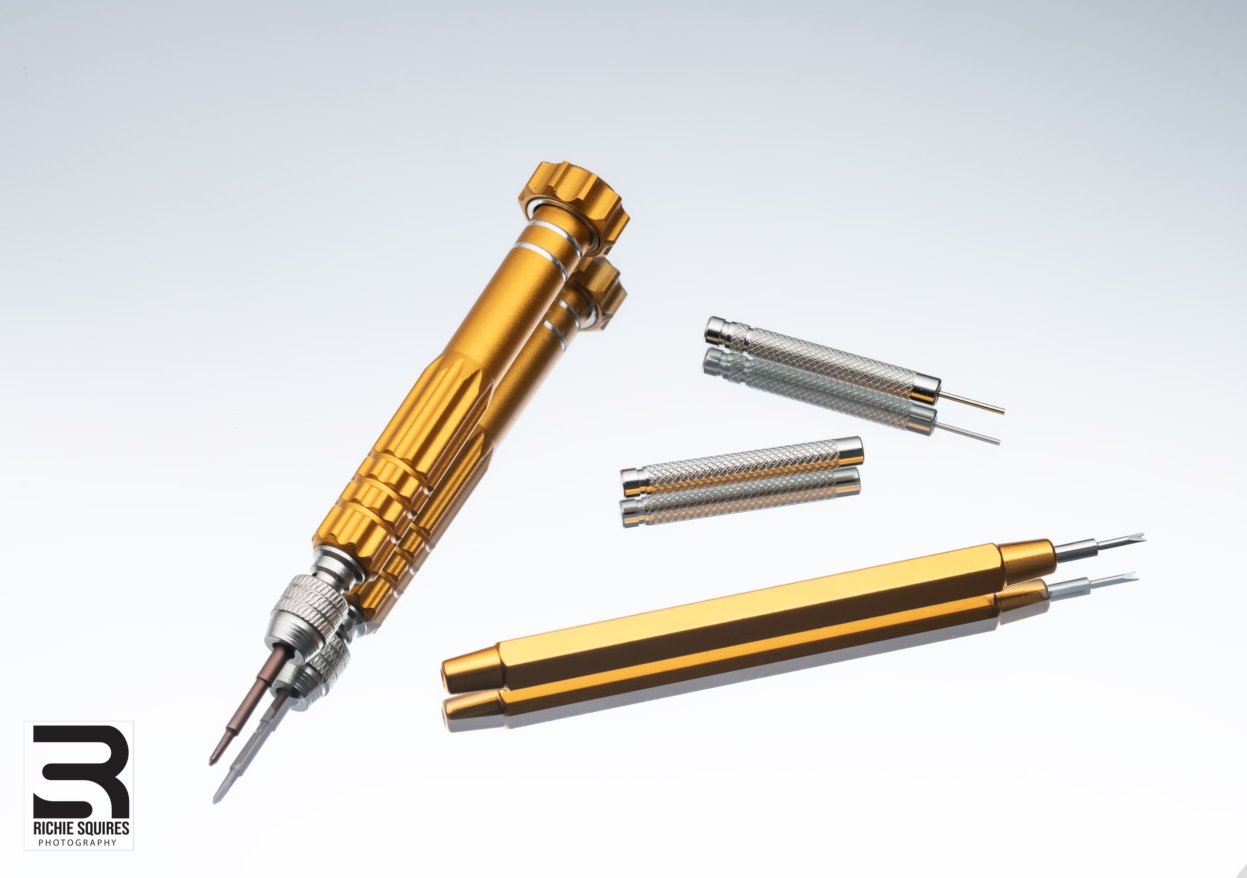 Gold and silver watchmaking tools on a white background