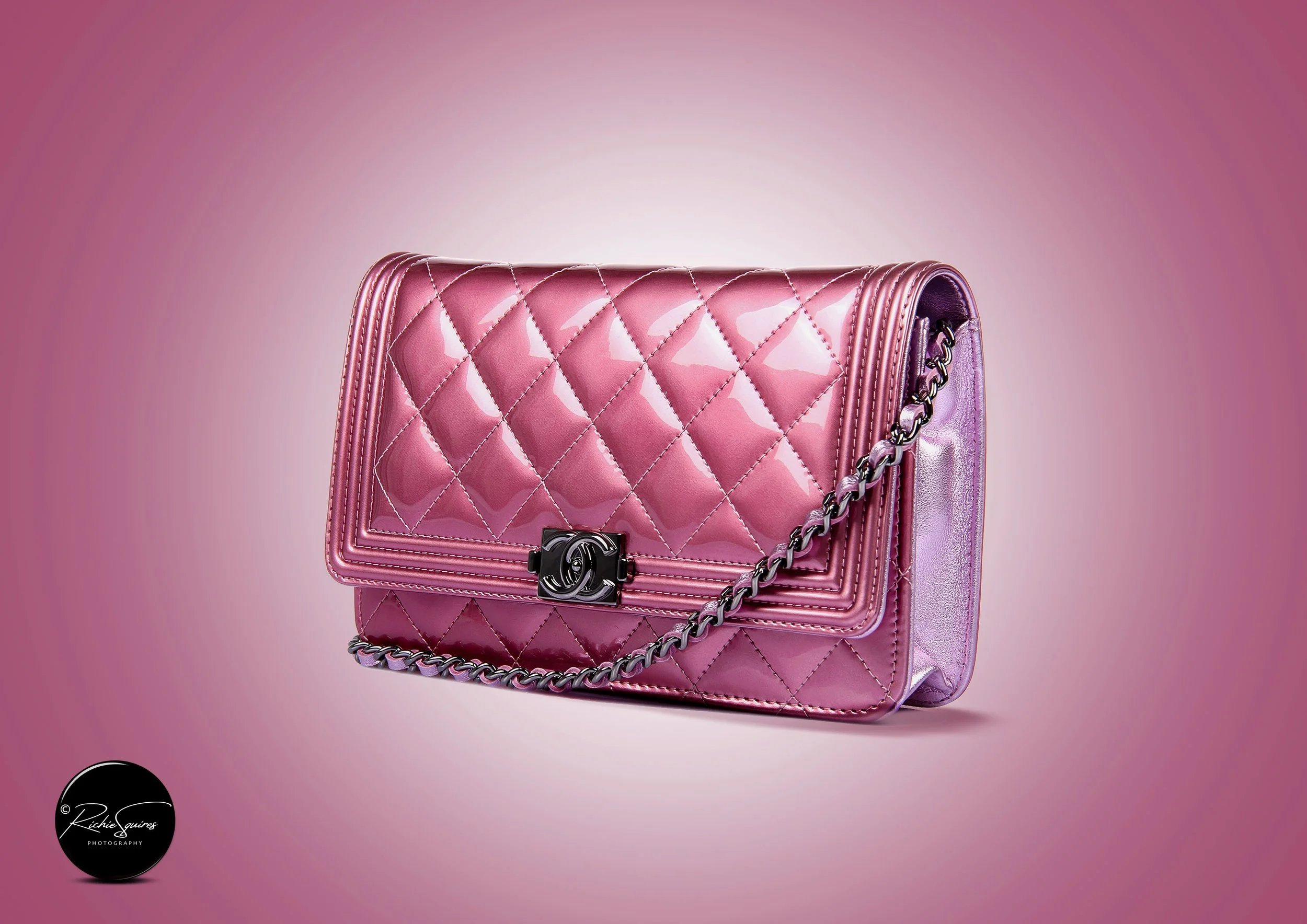 Pink quilted handbag with chain strap on a gradient background.