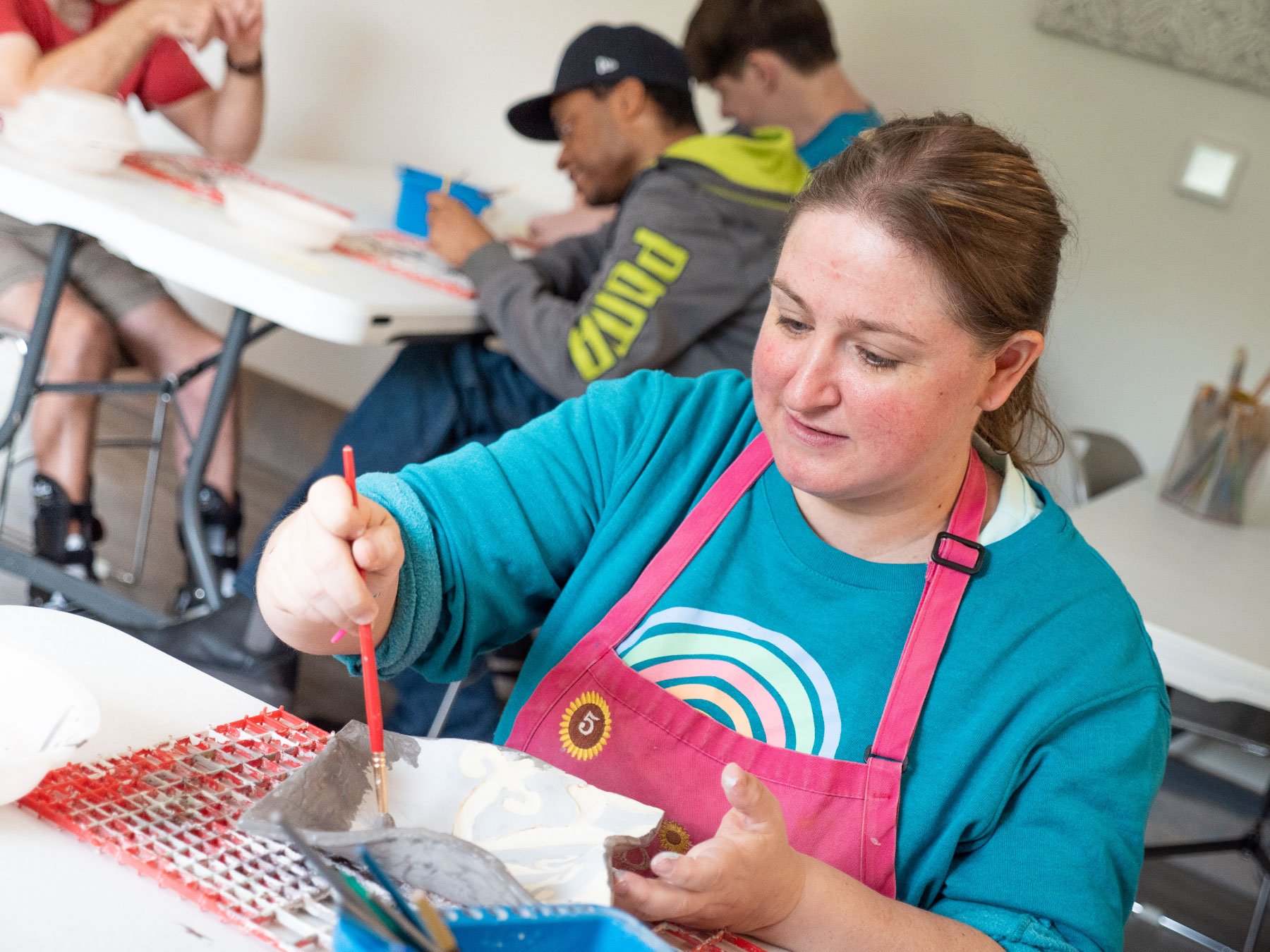 Woman-with-pink-apron-painting-pottery.jpg