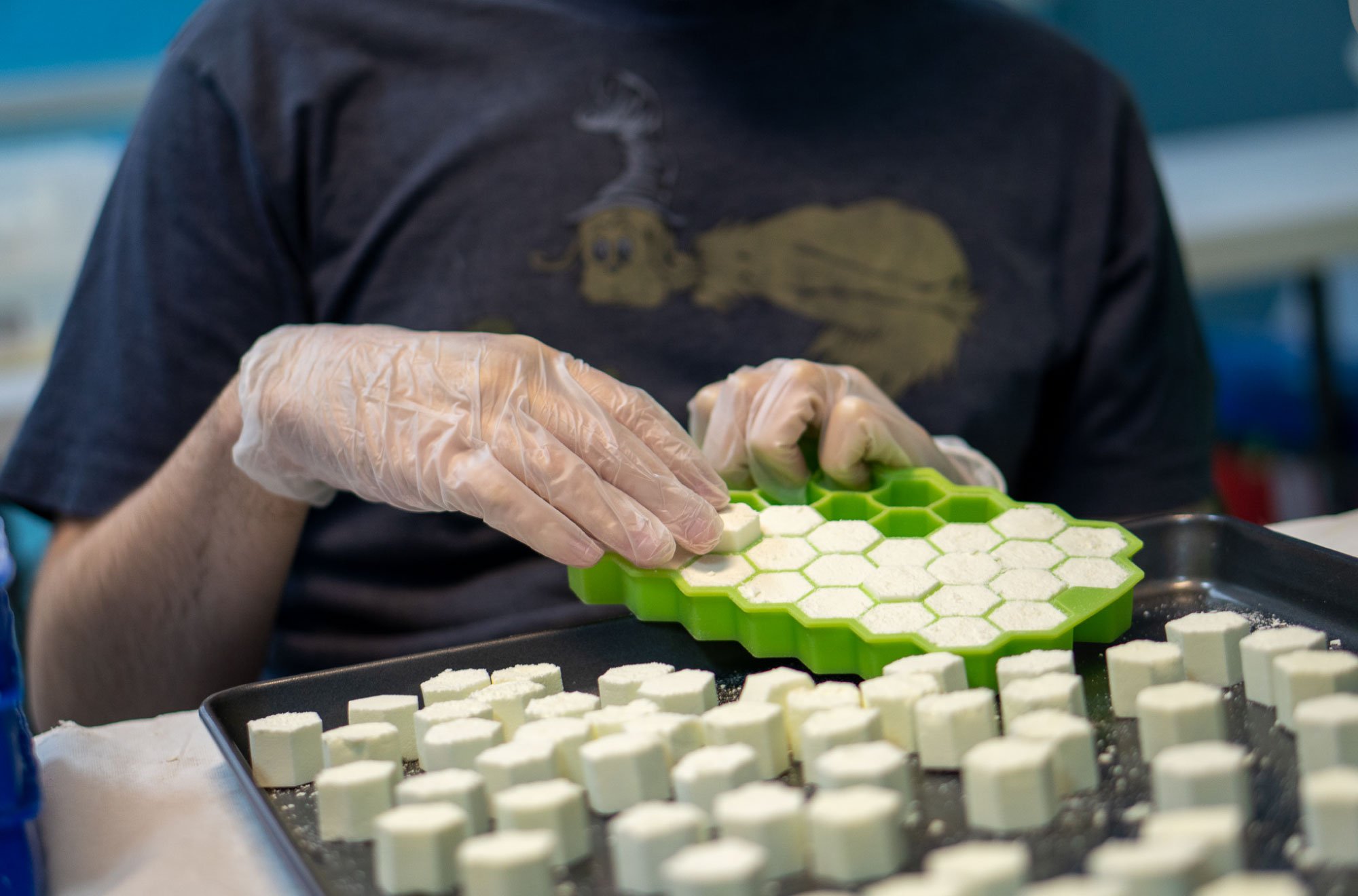 Man-wearing-blue-shirt-preparing-honey-comb-shaped-goods.jpg