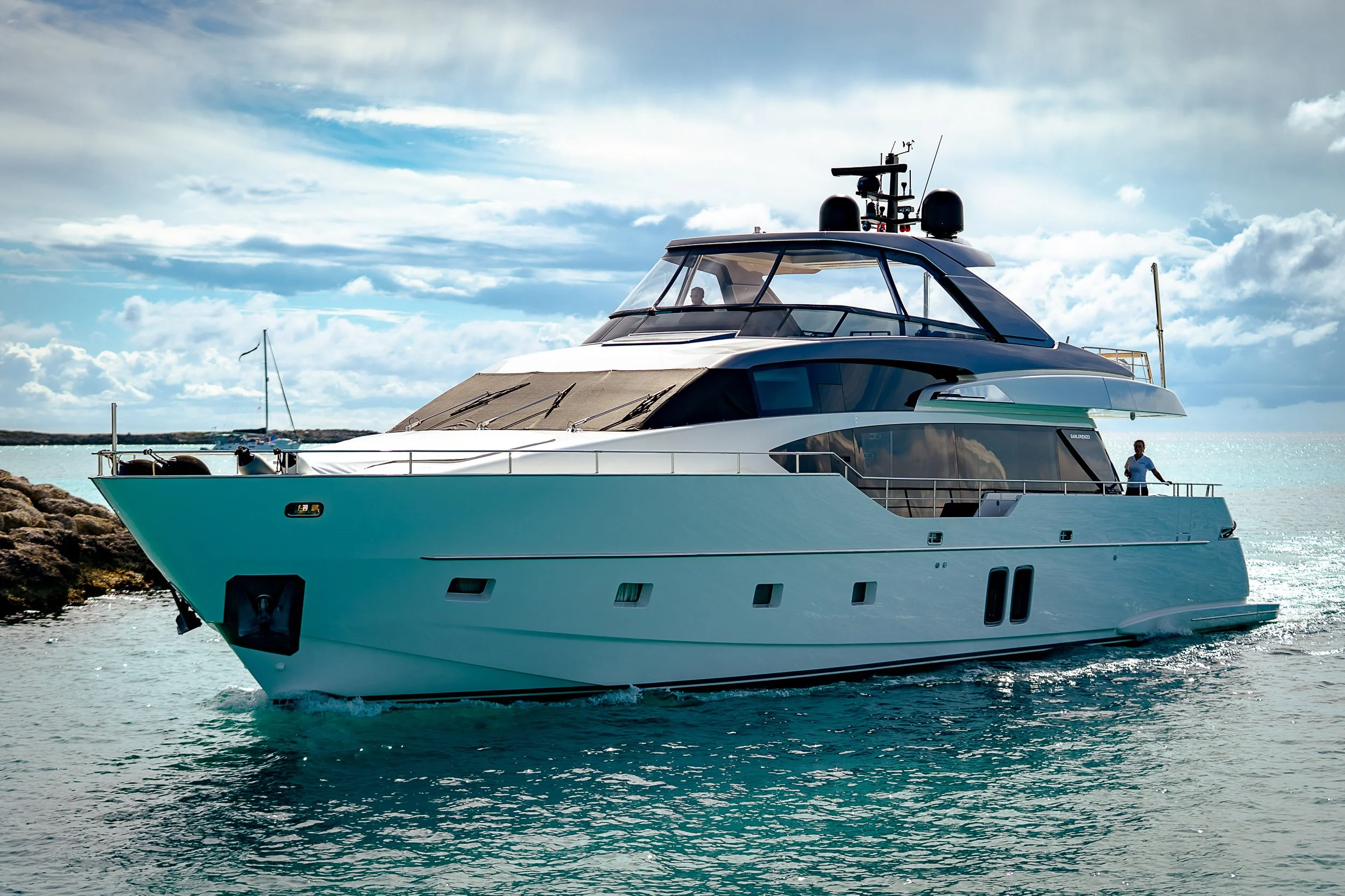 Luxury motor yacht cruising on a sunny day with a blue sky and calm sea.
