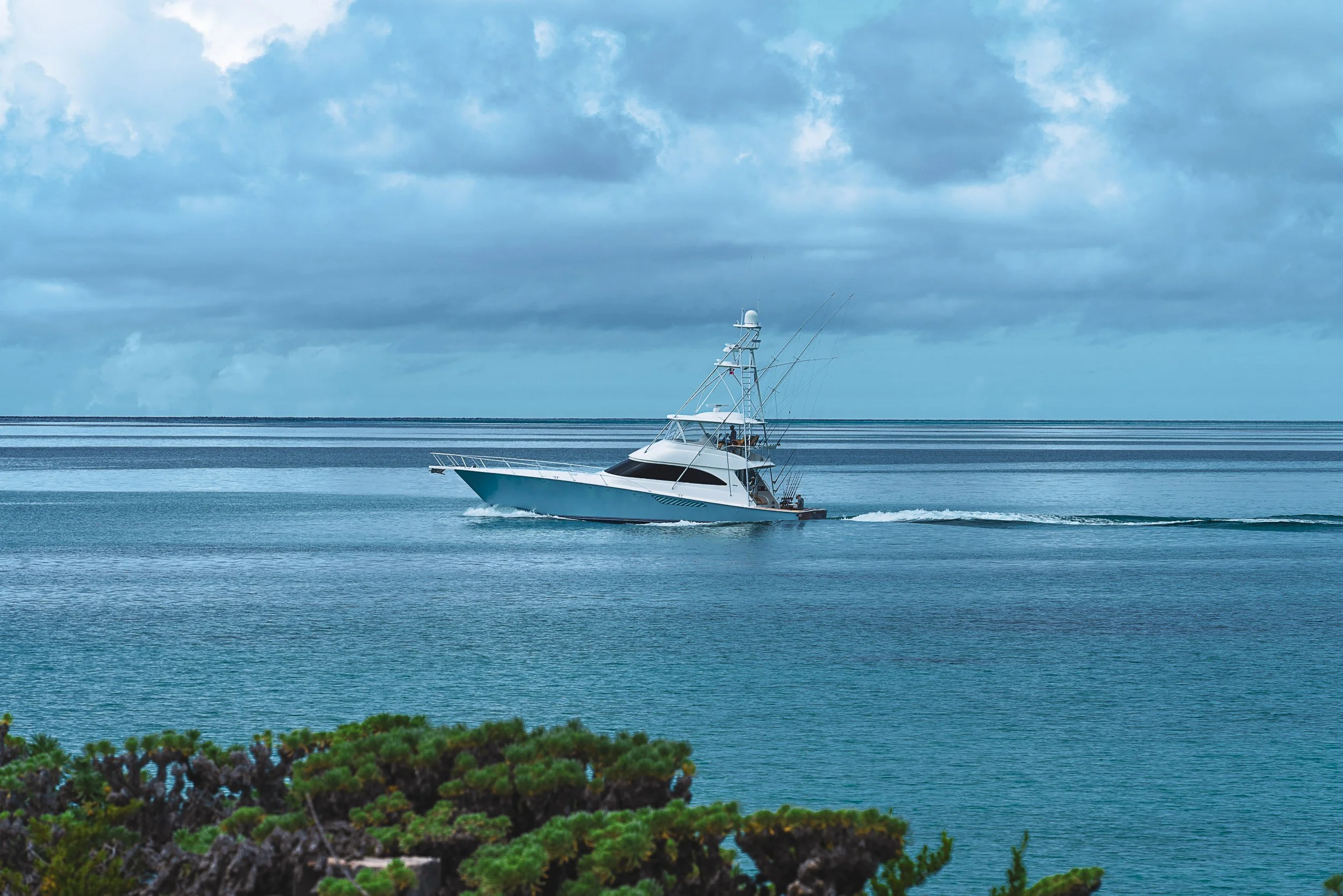 Fishing boat cruising on a calm ocean under cloudy skies.
