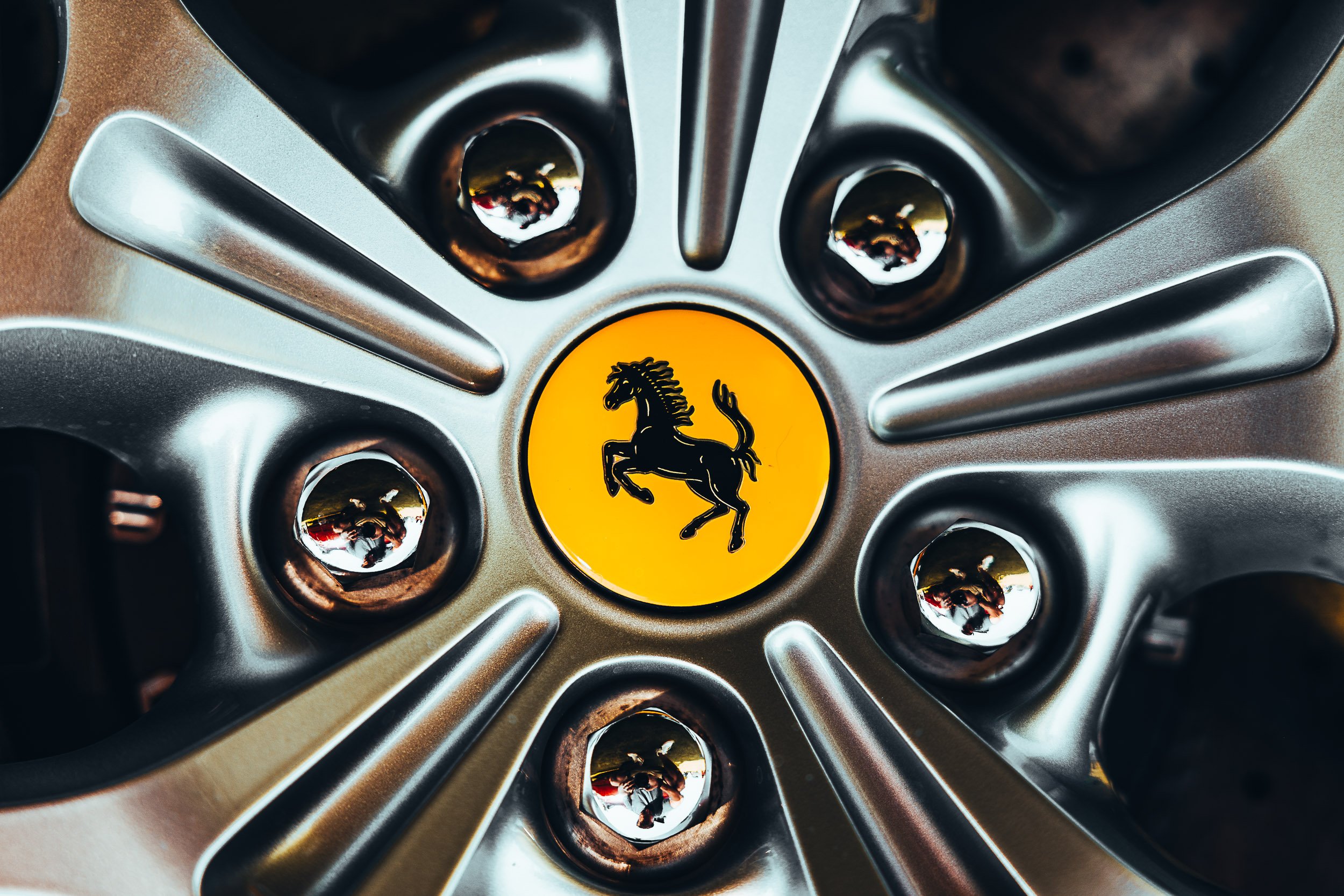 Close-up of a car wheel with a yellow emblem and black horse logo in the center.