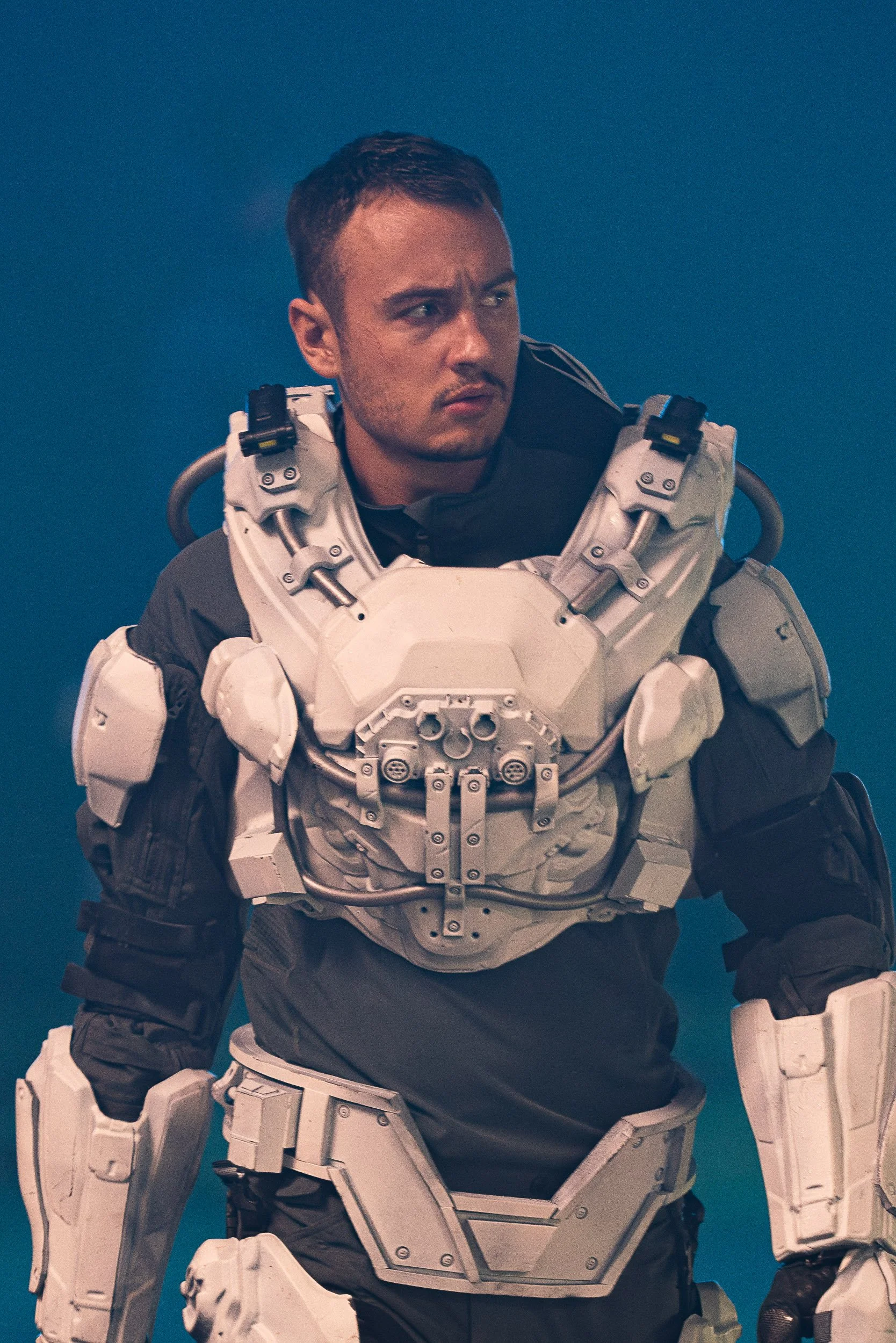 Person wearing futuristic white armor against blue background.